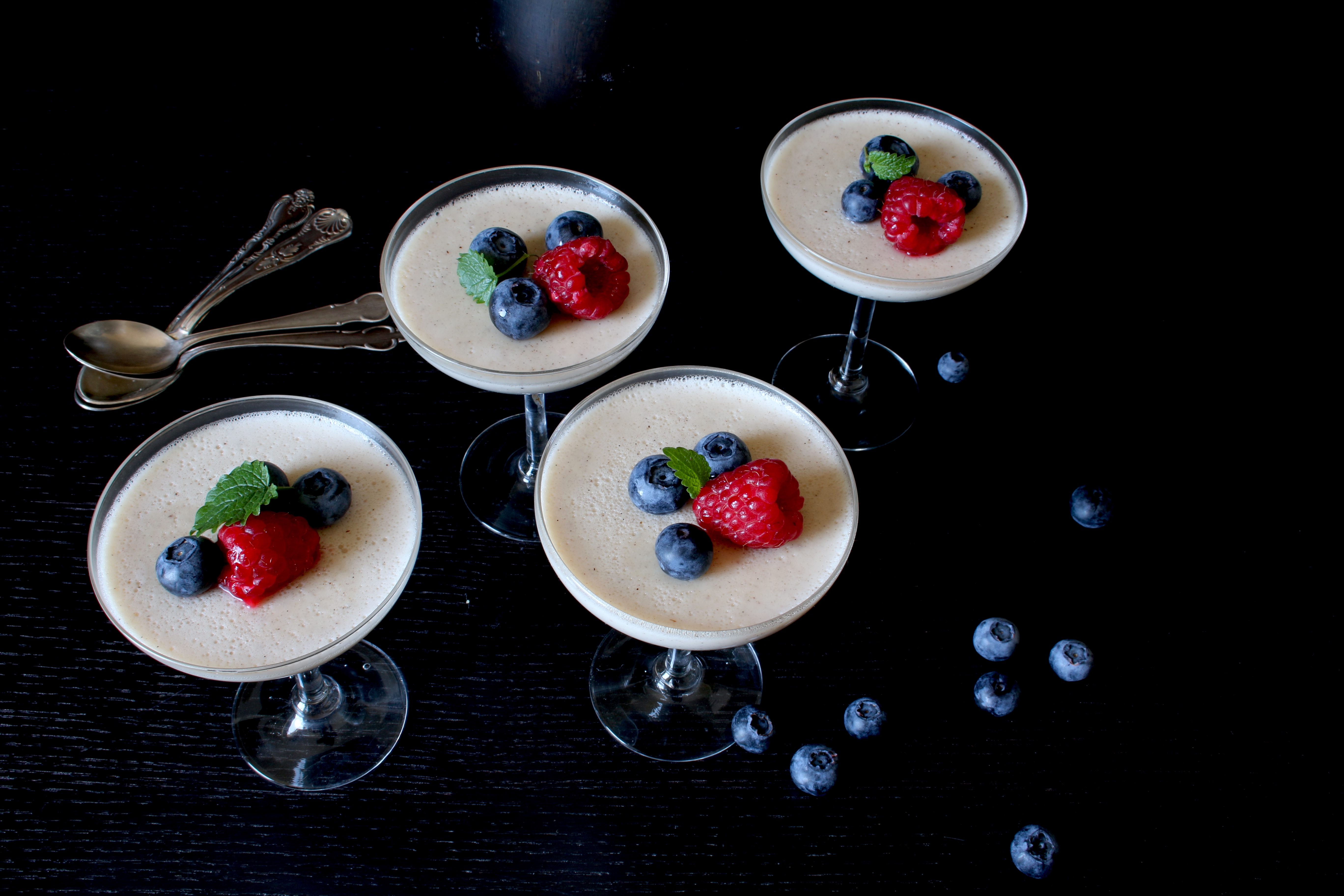 Pannacotta Fyra glas med pannacotta, dekorerad med hallon och blåbär.