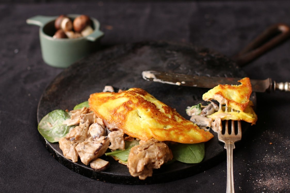 Vegansk omelette med Oumph Omelette med oumph på en svart tallrik på ett svart bord.