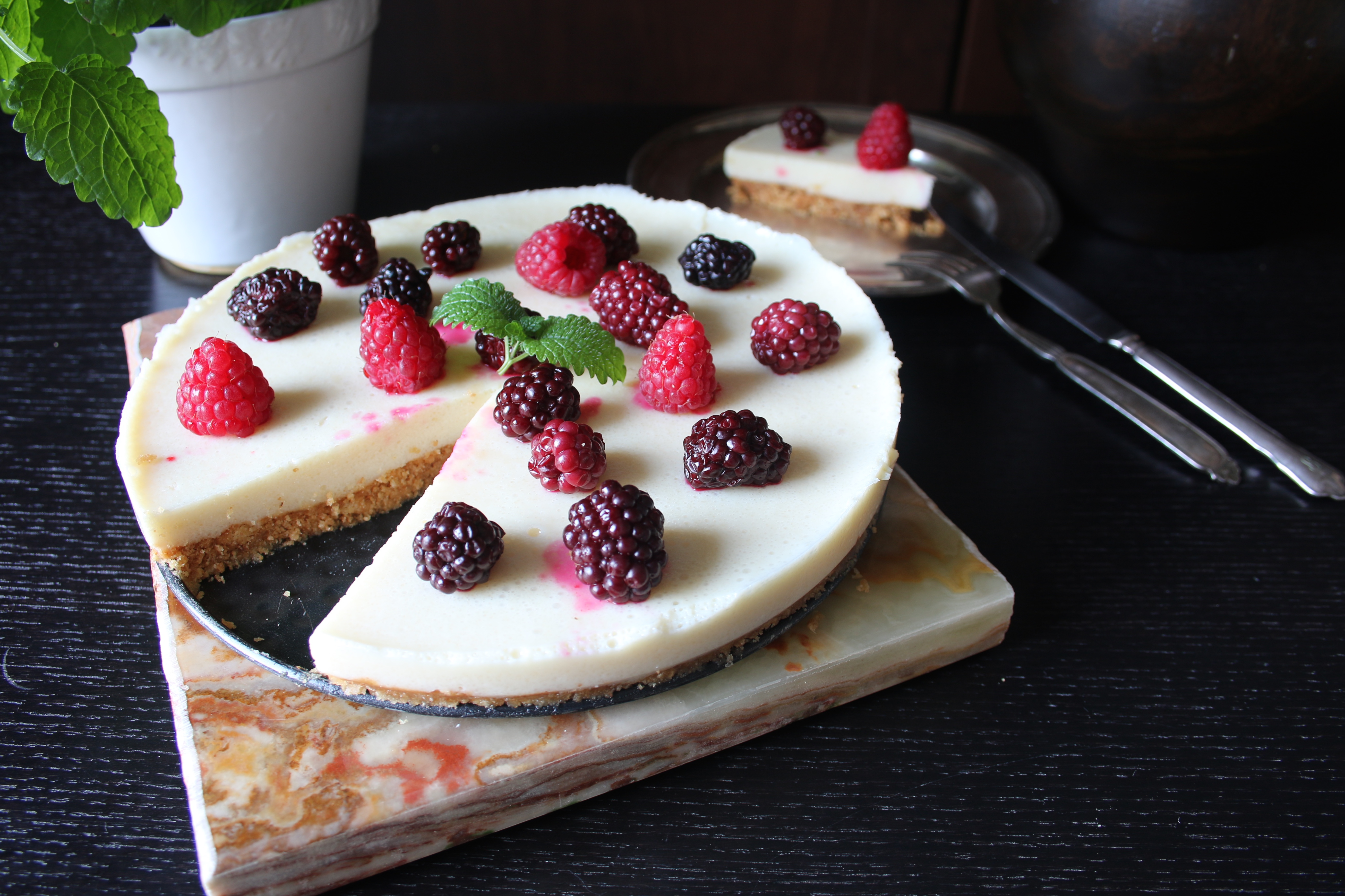 Cheesecake med citronfyllning Cheesecake med citronfyllning dekorerad med hallon och björnbär på ett mörkt bord