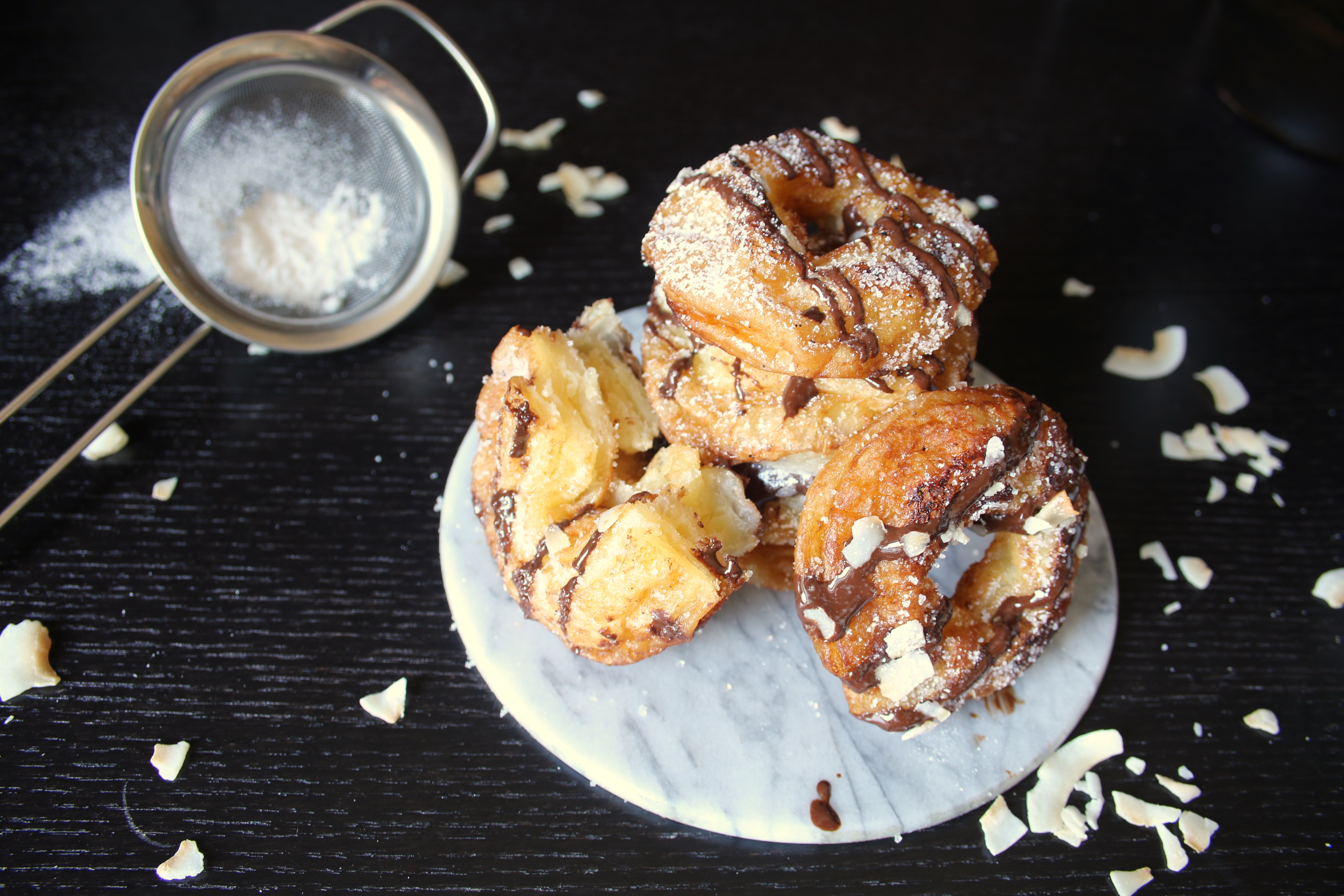Snabba cronuts Cronuts med choklad och kokosflarn på ett vitt fat på ett mörkt bord