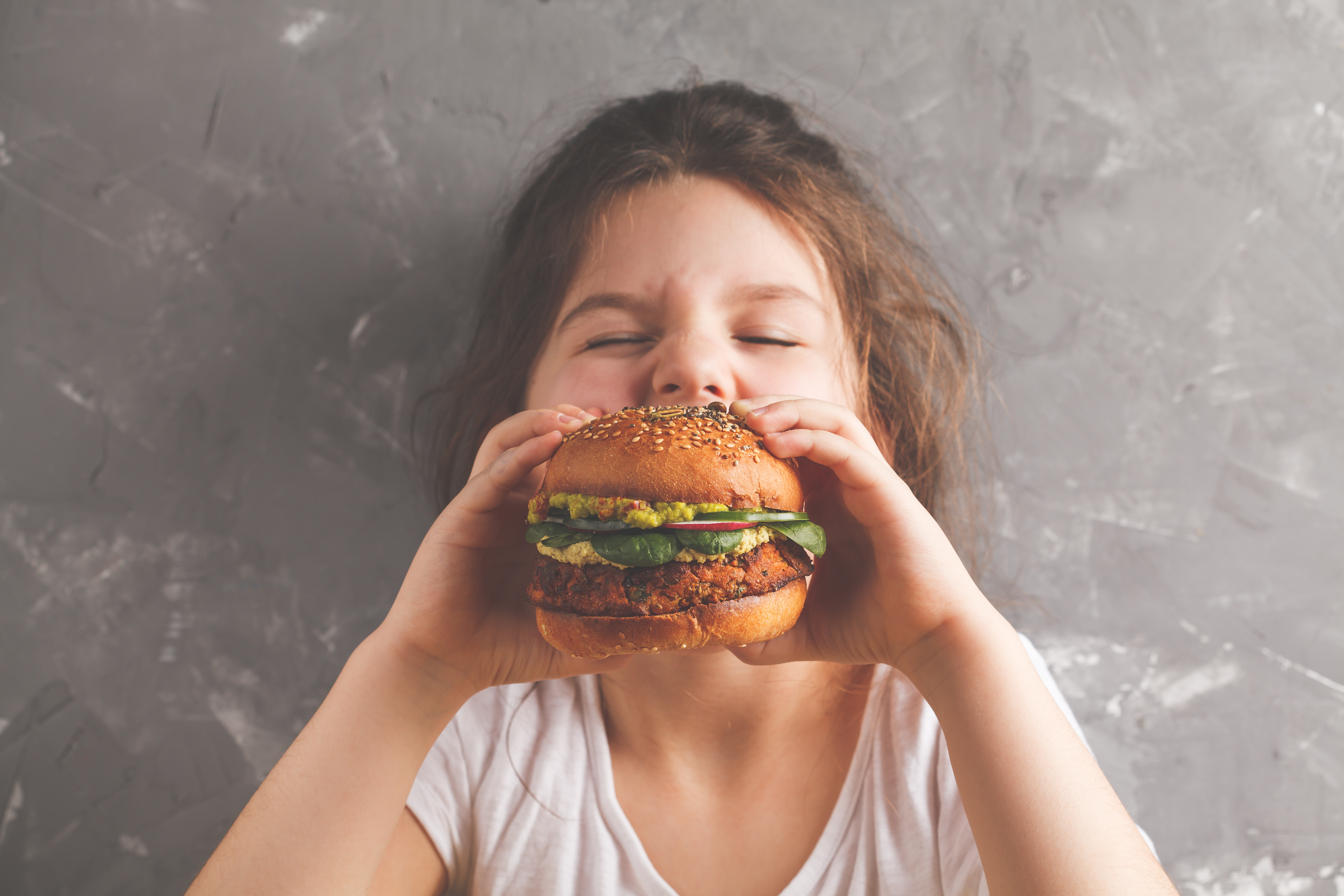 Shutterstock - Nina Firsova Ung barn äter hamburgare