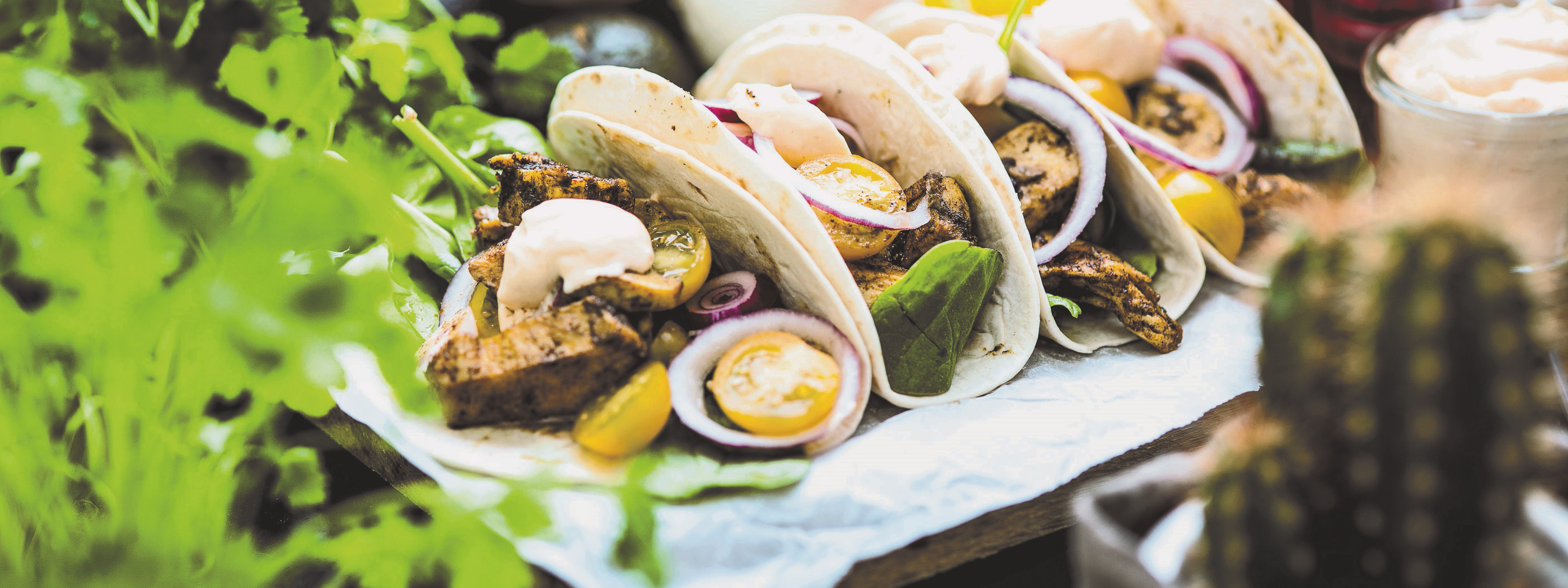 Jamaican jerked taco Fyra stycken tacos ligger på en vit handduk, i förgrunden syns gröna blad