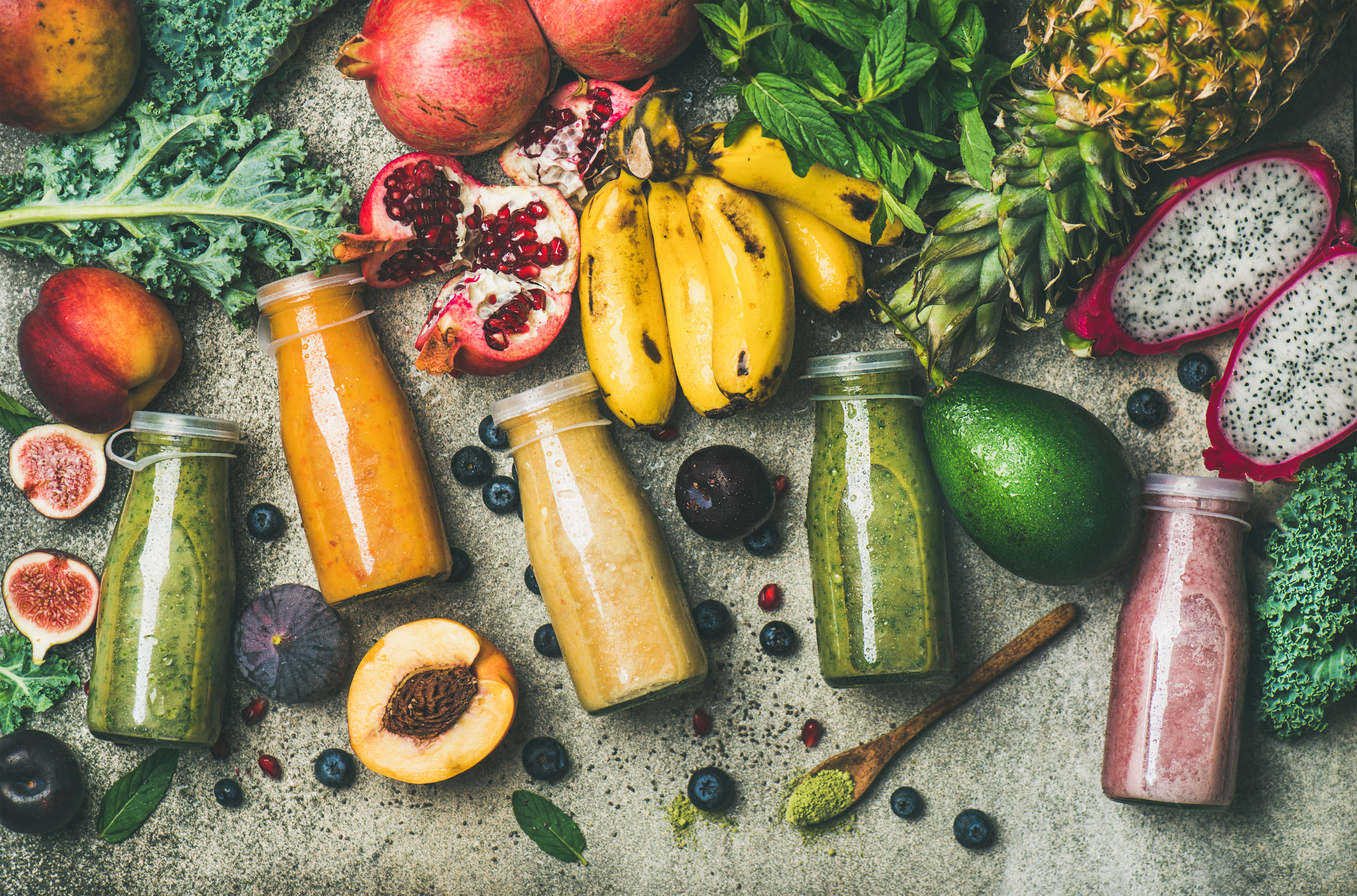 Diverse frukter och juicer i glasflaskor utspridda på ett bord