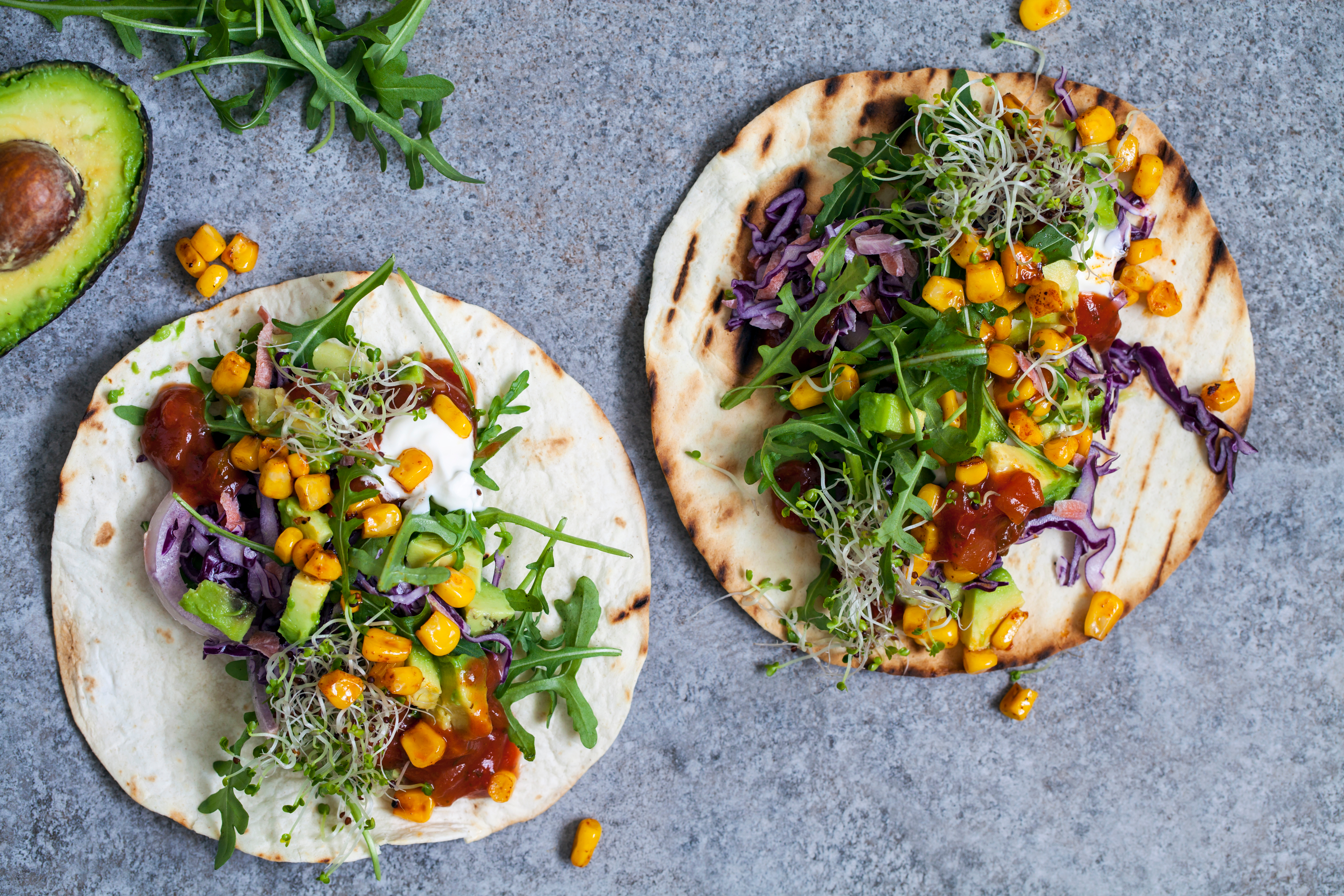 Öppna tortillabröd med grönt och pulled jackfruit på ett bord