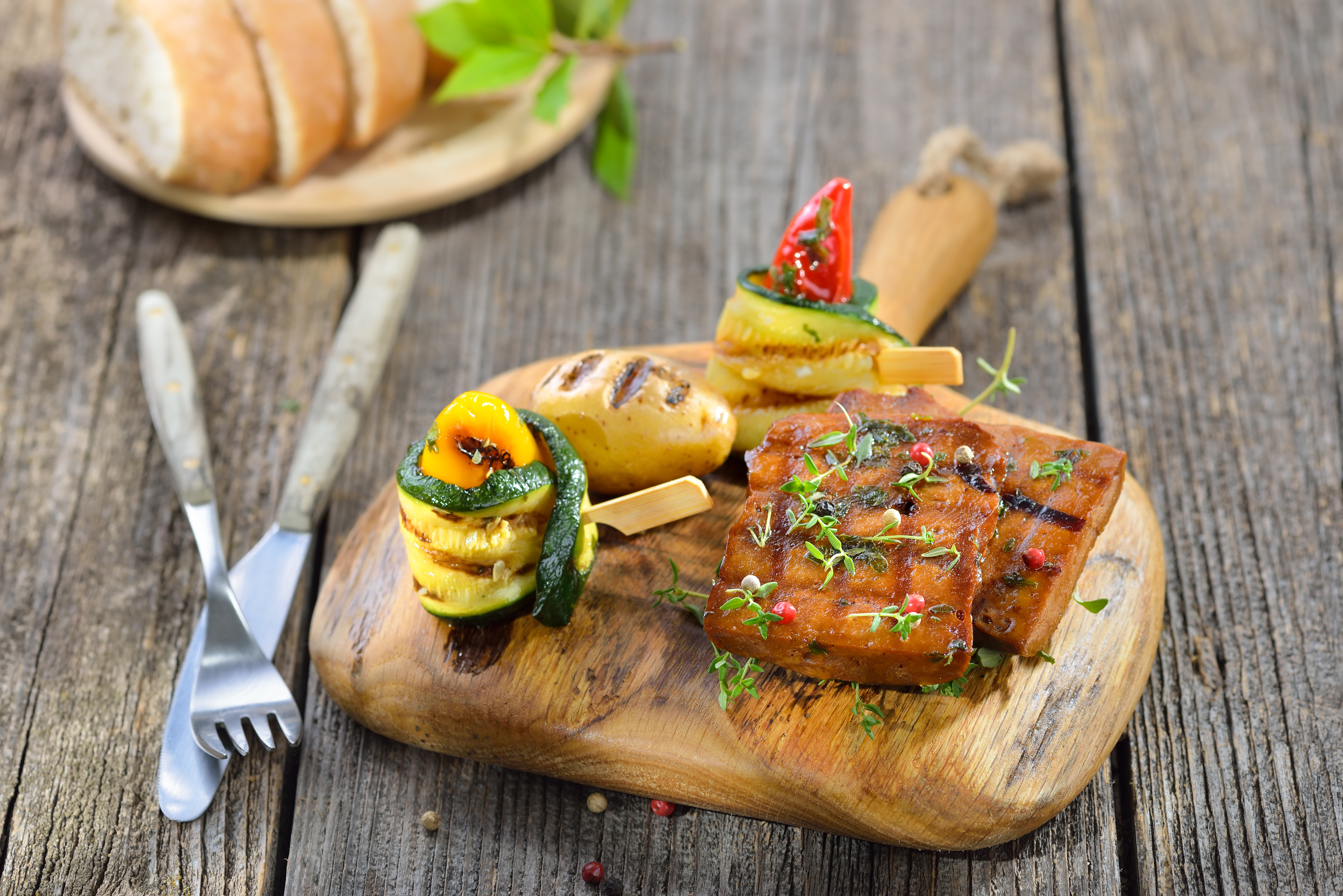 Vegansk seitan på en träbräda intill grönsaker