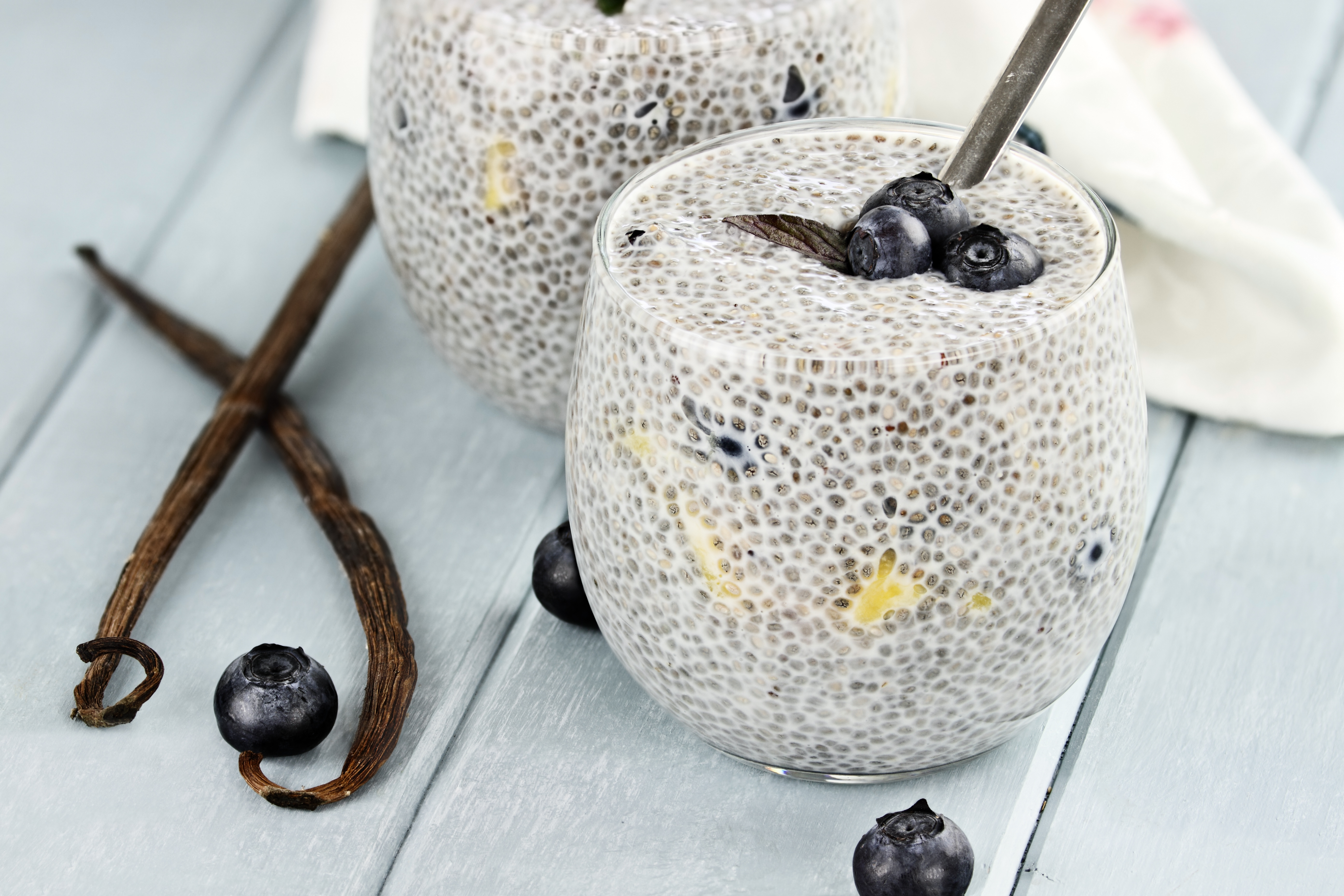 Chiapudding i ett glas med några blåbär på ett bord.