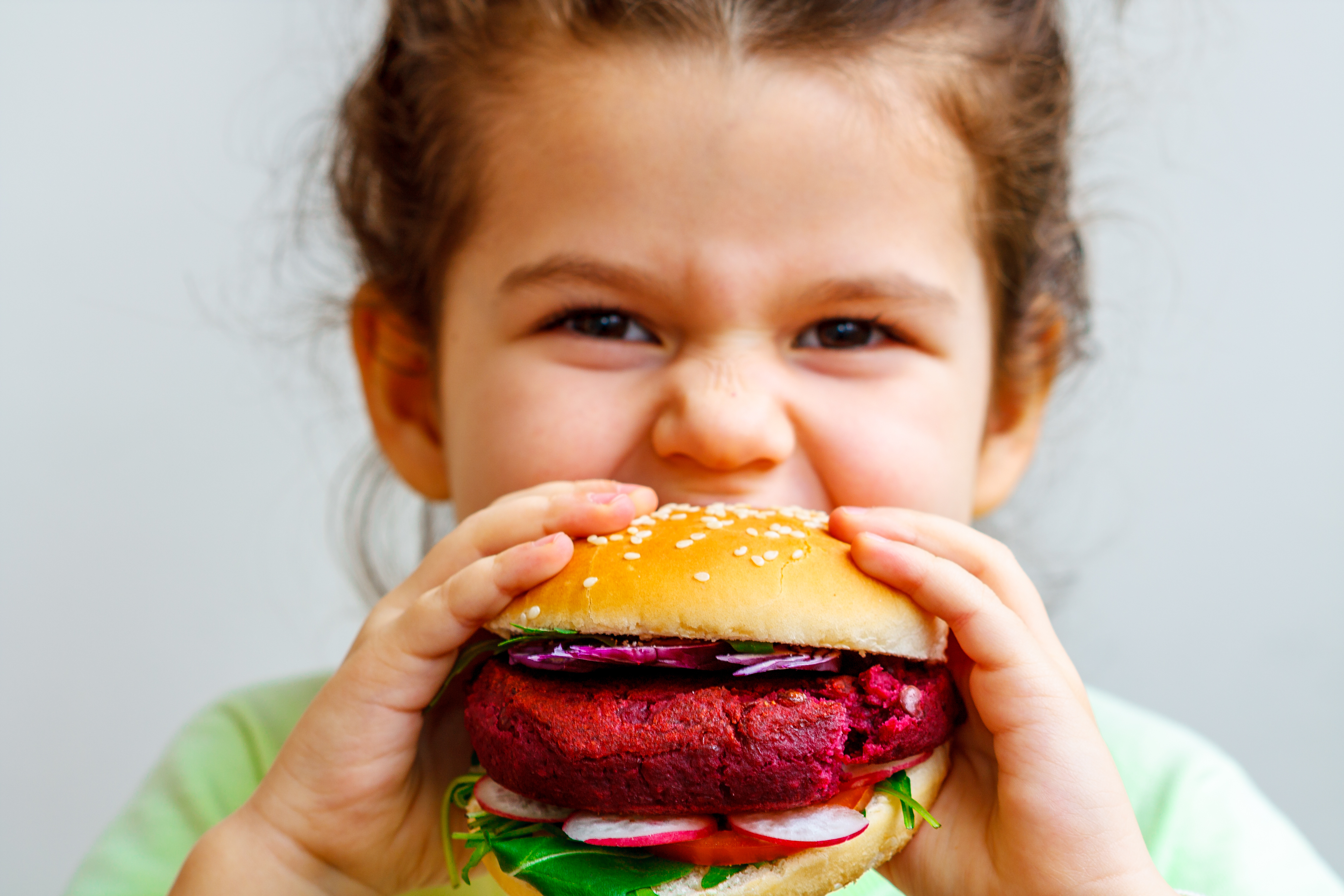 Ett barn tar en tugga av en vegansk burgare