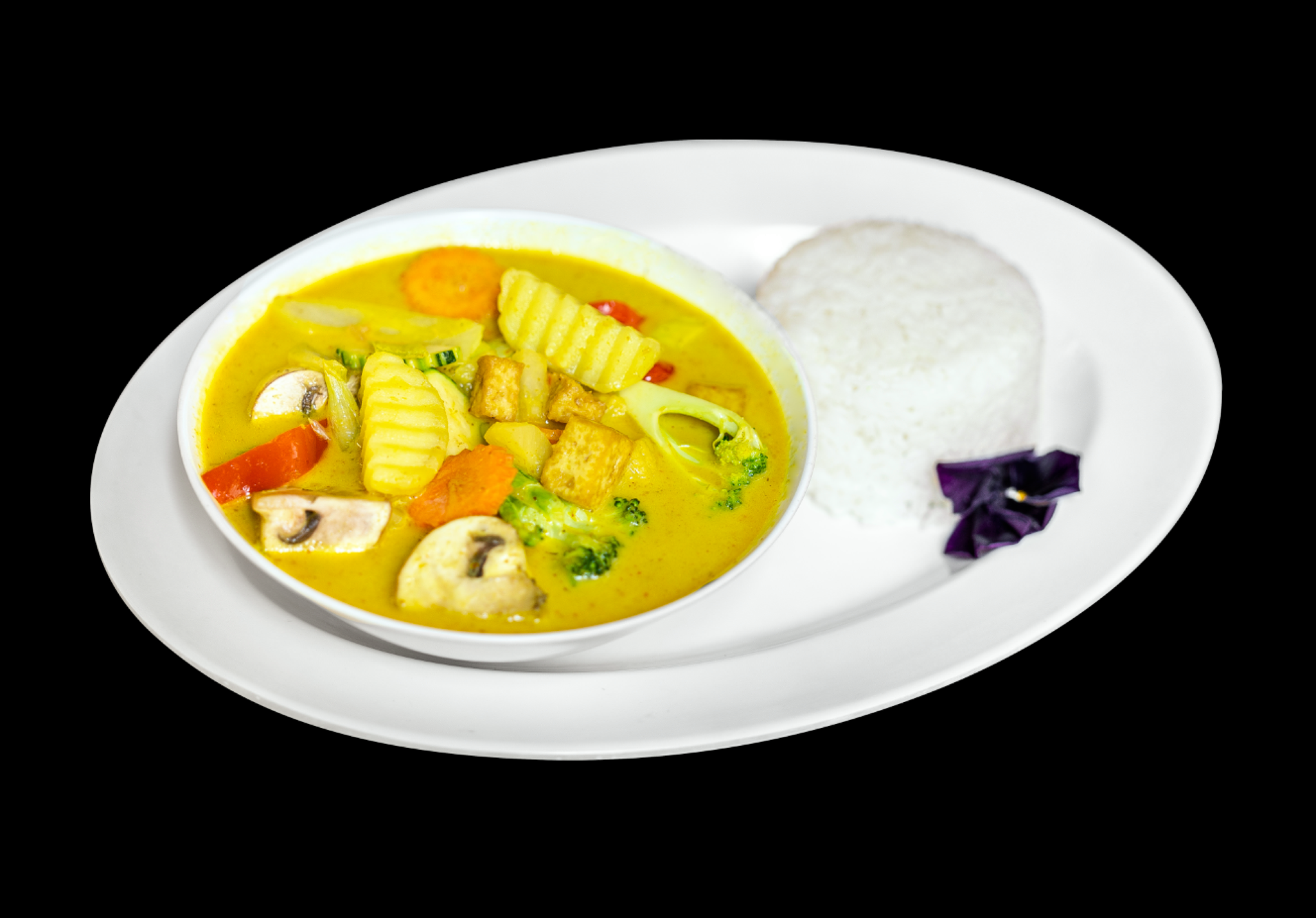 Foto: webbtech.nu Mae Thai Stockholms veganska gula curry med tofu, grönsaker och ris på en vit tallrik med svart bakgrund.