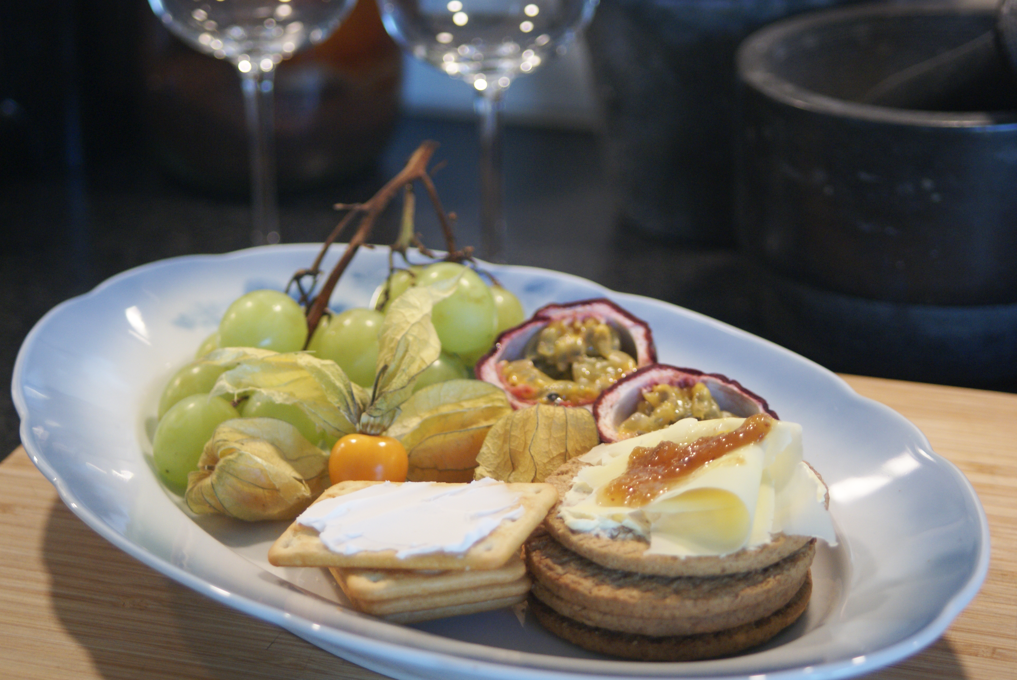 Foto: Välj Vego Vegansk ostbricka med kex och frukt. I bakgrunden skymtas två vinglas.
