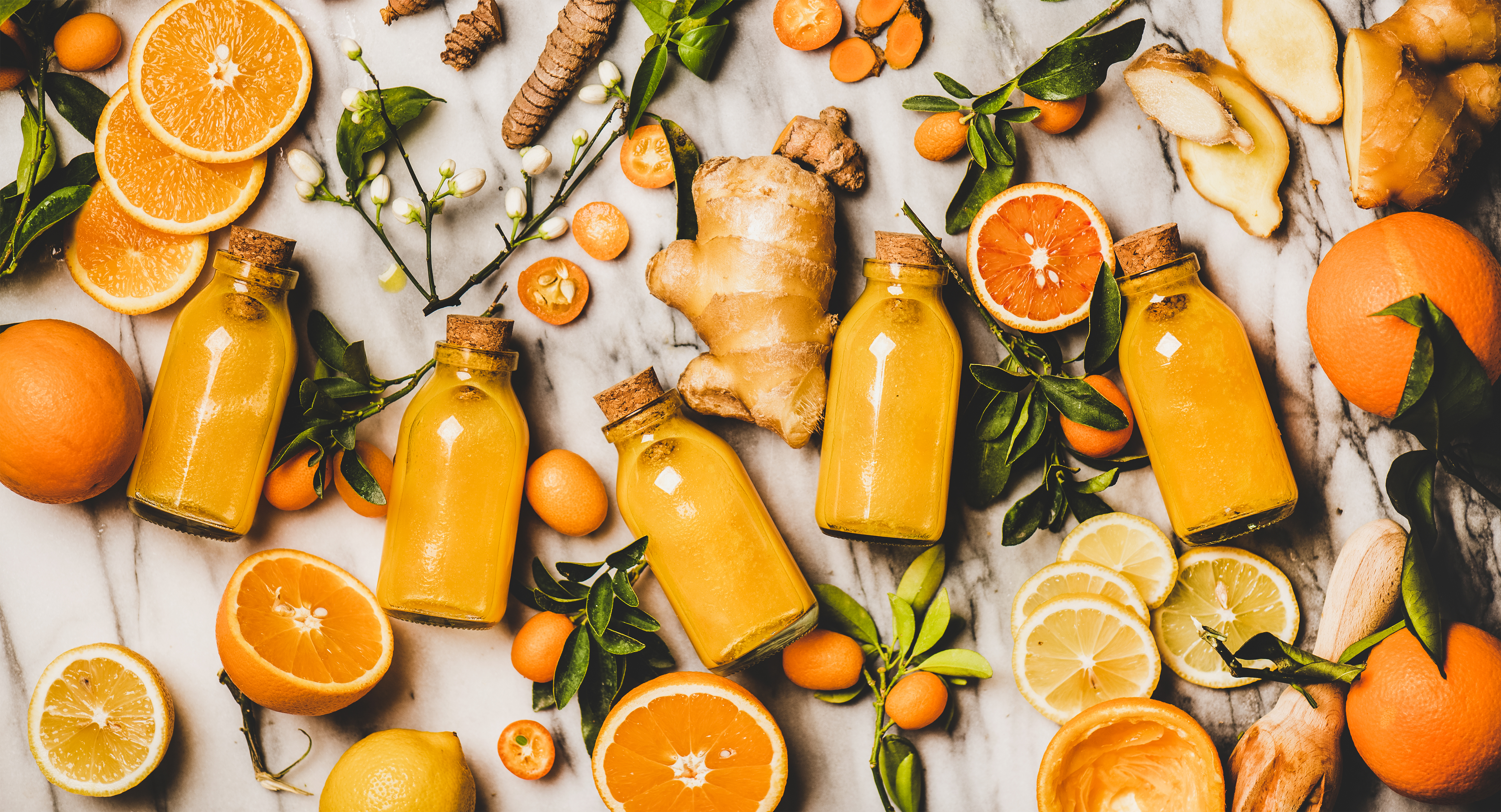 Foto: Foxys Forest Manufacture / Shutterstock Apelsin, ingefära och små flaskor med apelsinjuice, utlagt över yta.