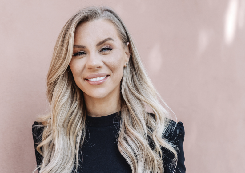 Foto: Amanda Parkkinen Therése Lindgren leendes framför beige vägg med solkatter