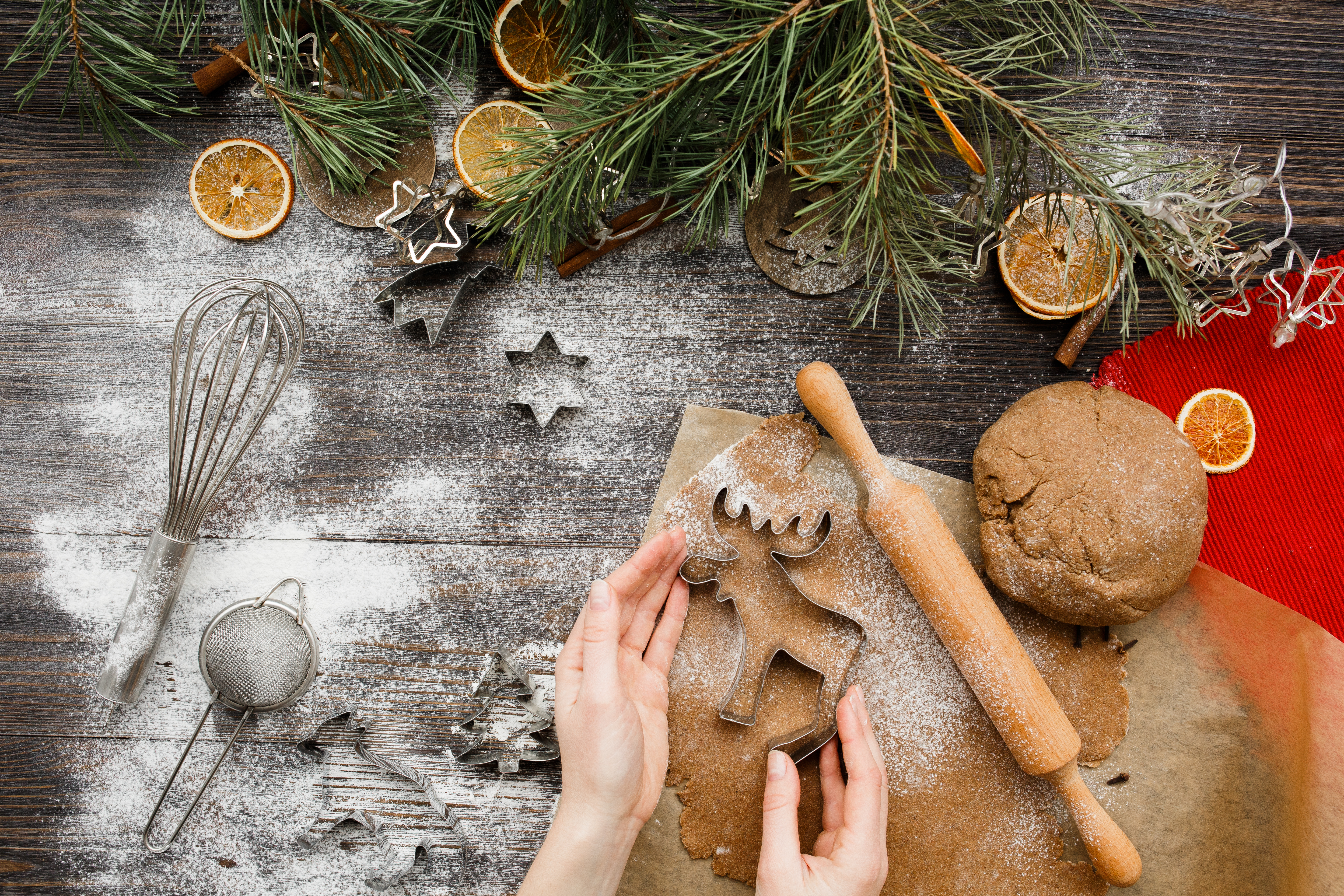 Foto: artteam/Shutterstock Pepparkaksbak på mjöligt bord med tallbarr och torkade apelsinskivor.