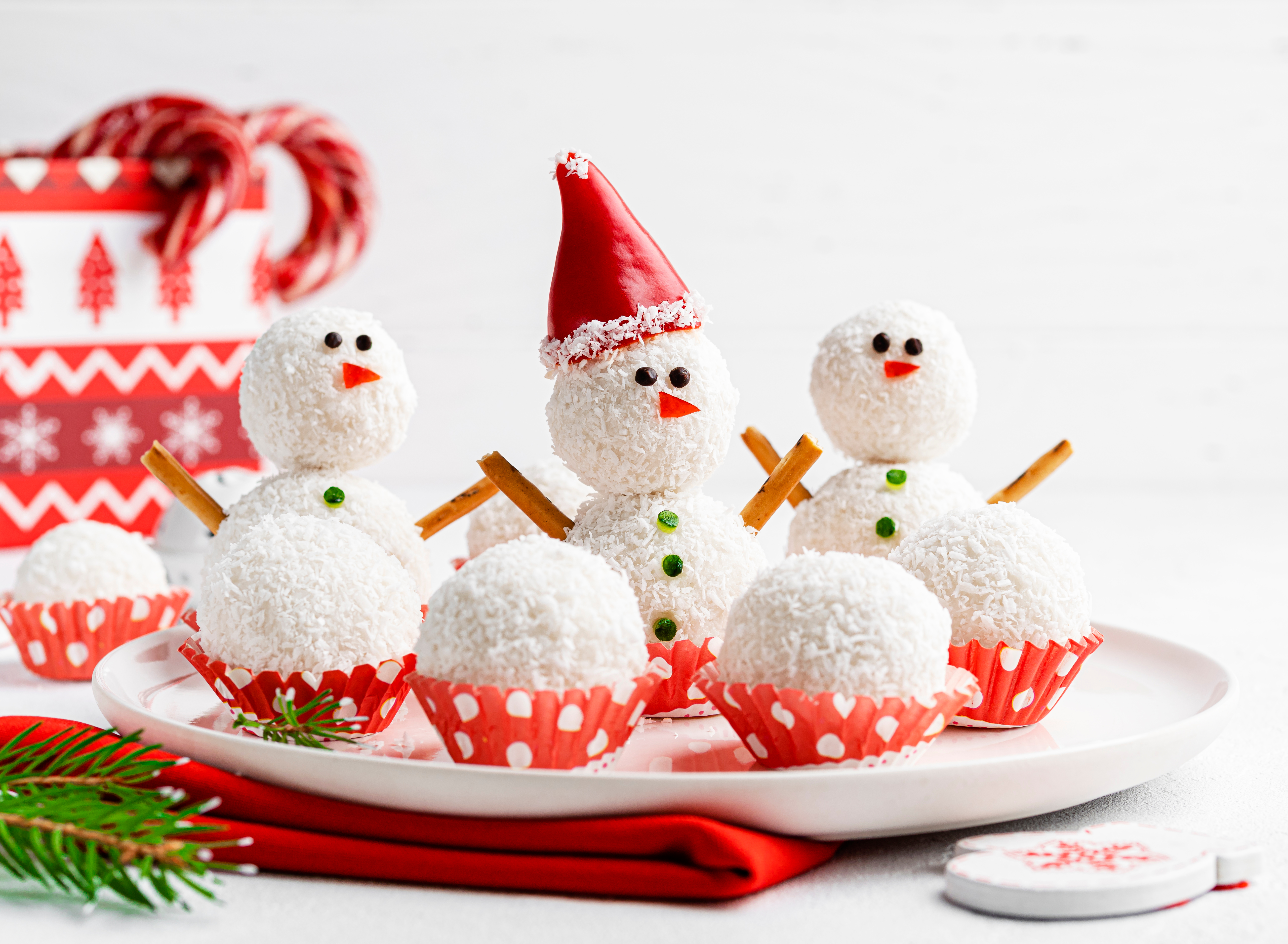 Foto: Alena_Kos/Shutterstock Snögubbar gjorda av kokosbollar i tomteluva. Hälsosam juldessert. Roliga och söta nyårsgodis. Festlig mat. Vinter och jul koncept. Gran grenar, godis. Vit bakgrund.