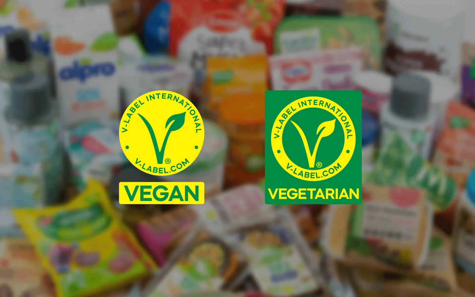 Produktfoto: V-Label Två uppdaterade V-label loggor mot en suddig bakgrund av livsmedelsprodukter