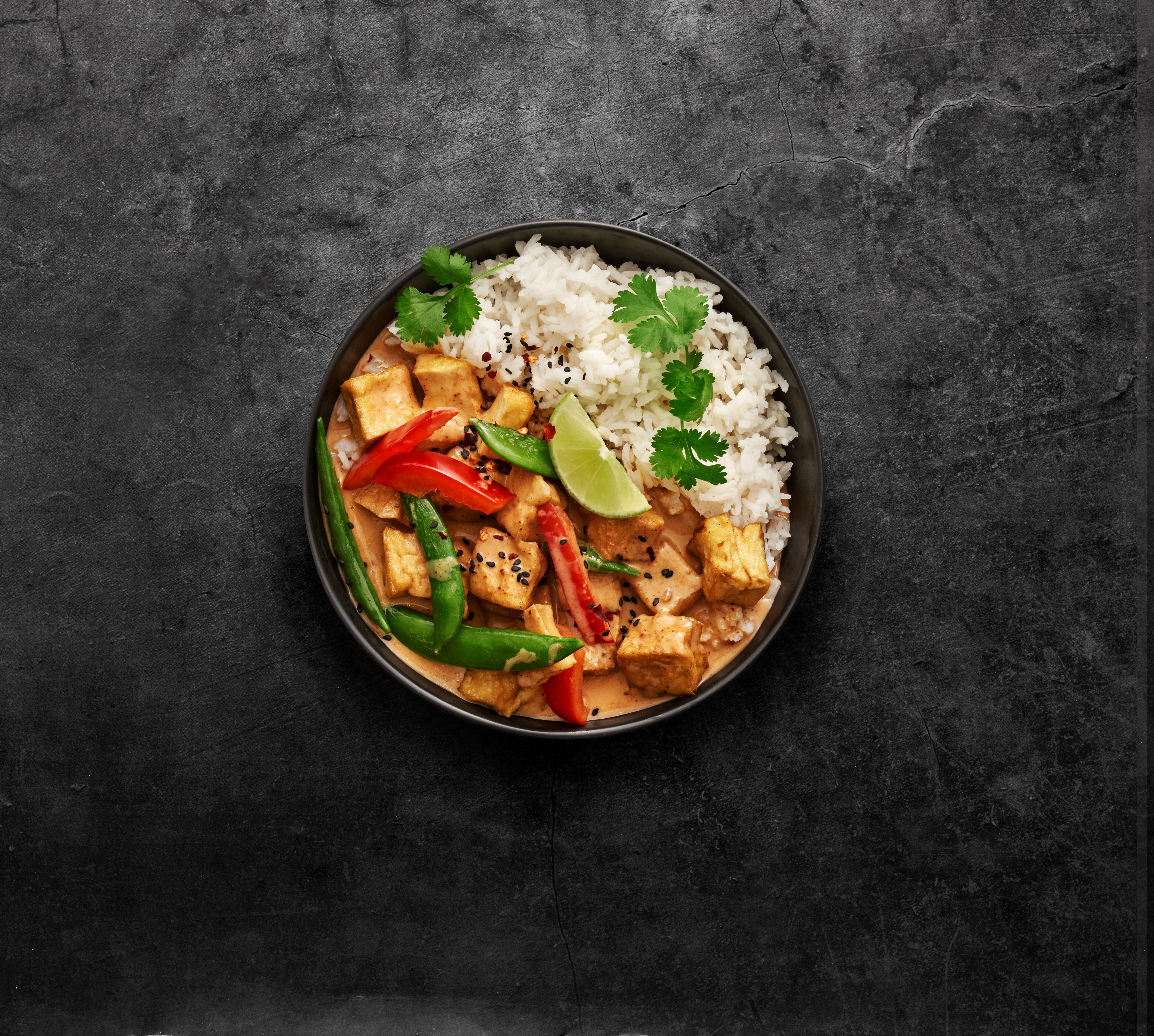 Produktfoto: Emma Shevtzoff röd currygryta med ris i en djuptallrik vinkel uppifrån mot en granitgrå bakgrund