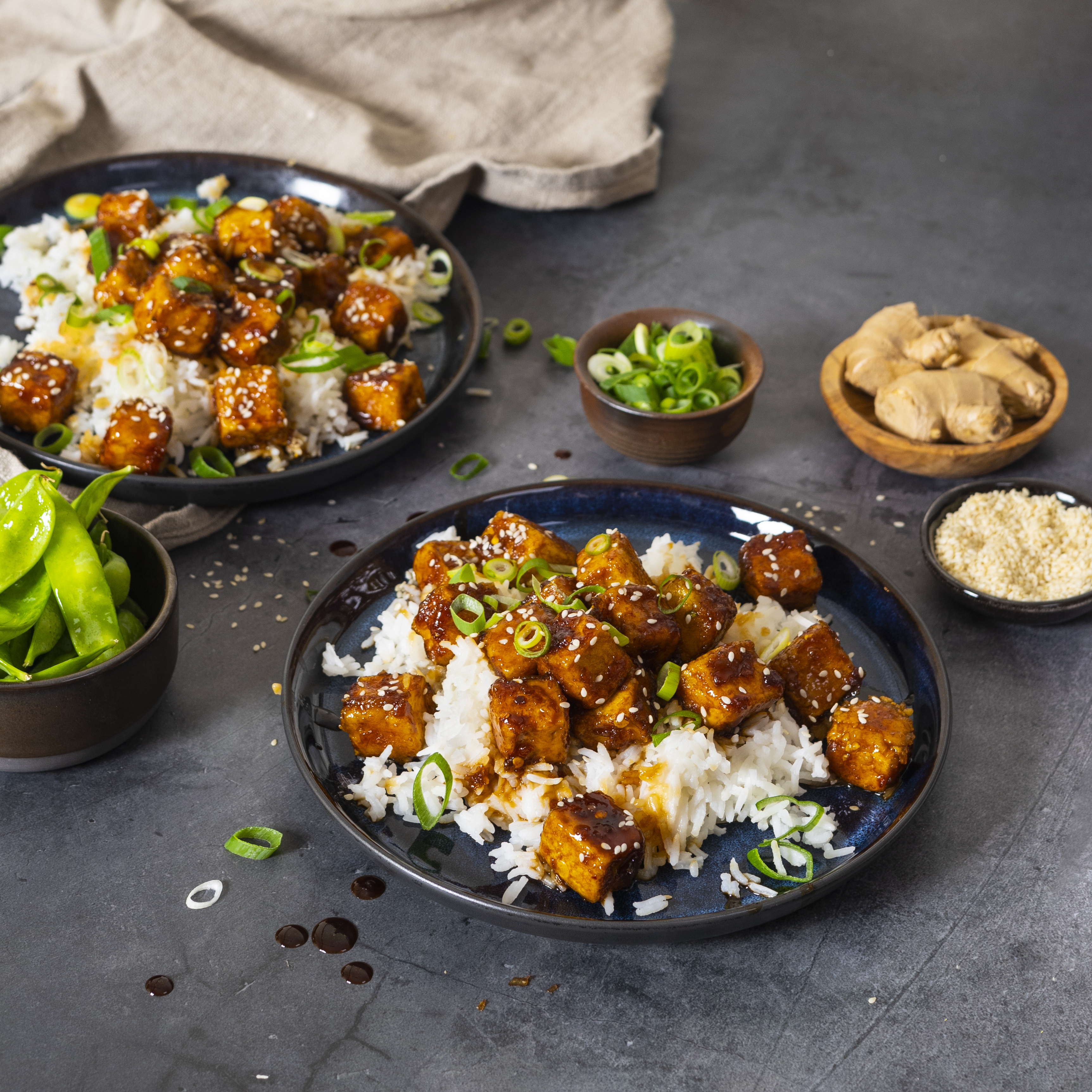 Produktfoto: Yipin Två djuptallrikar med general tso tofu på ett mörkgrått bord