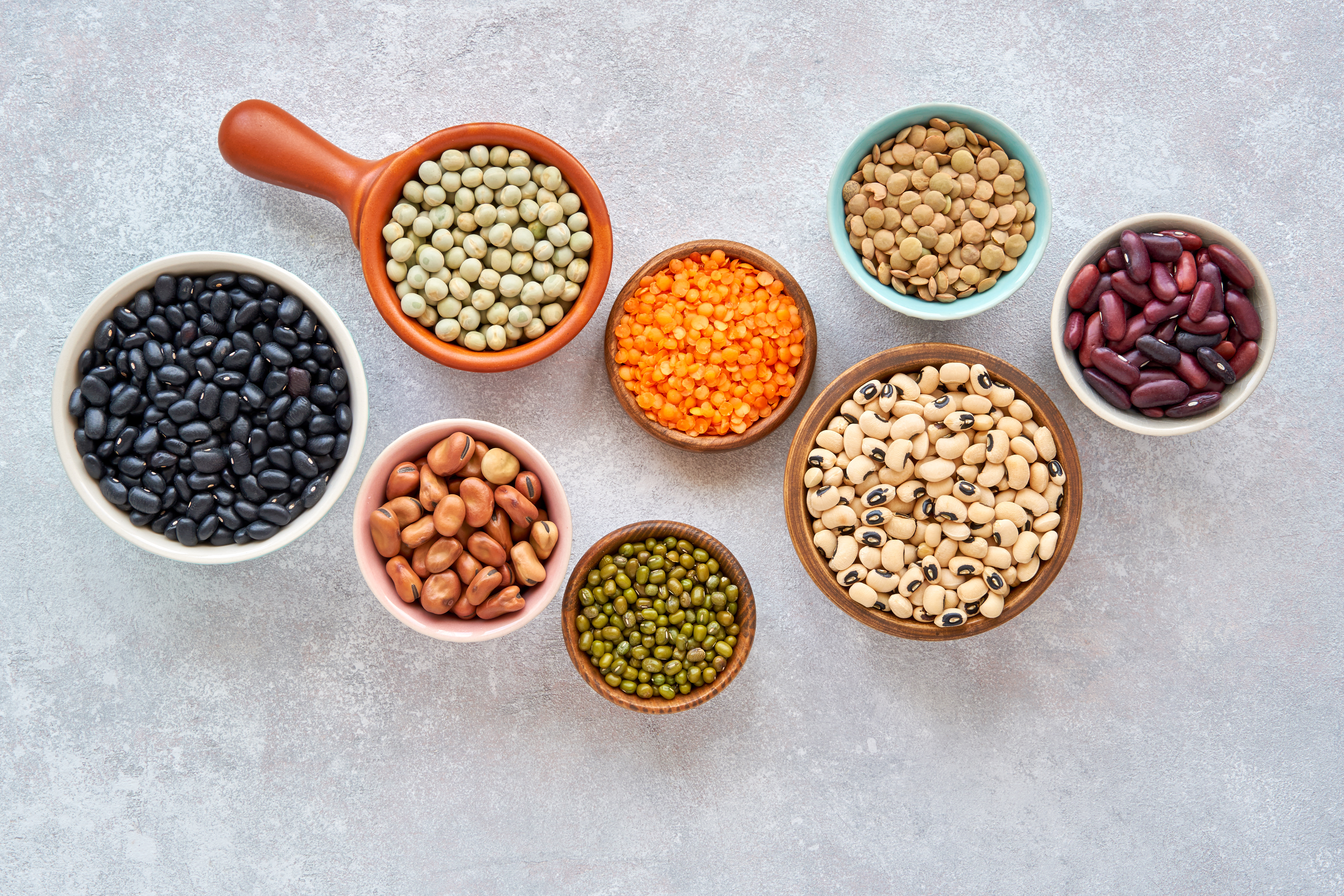 Foto: Veliavik/Shutterstock Baljväxter och bönor sortiment i olika skålar på ljus sten bakgrund. Toppvy. Hälsosam vegansk proteinmat.