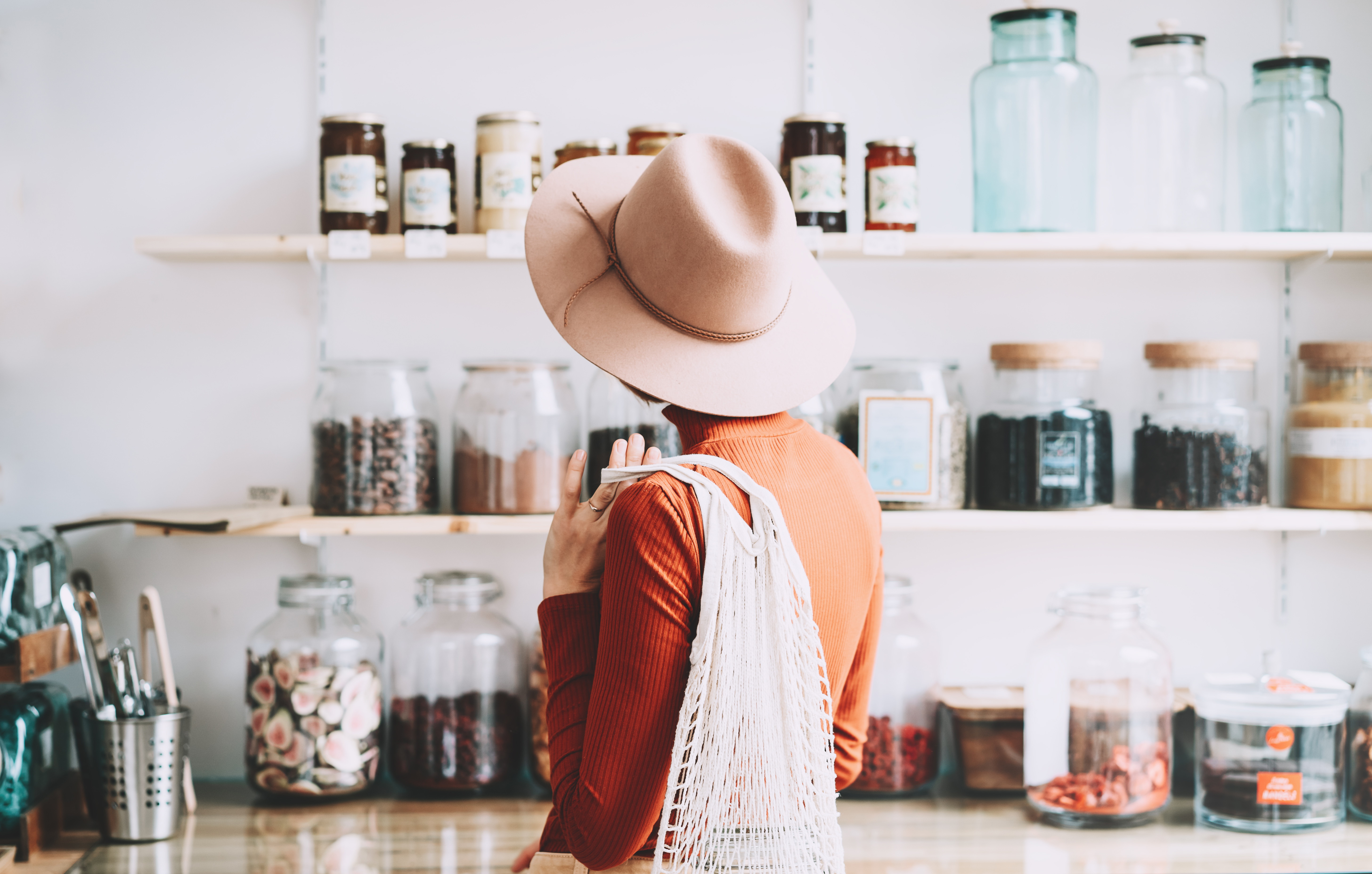 Foto: Natalia Deriabina/Shutterstock Minimalistisk vegansk stil ung kvinna med bomull återanvändbara nät väska på bakgrund av varor av noll avfallsbutik. Shopping utan plastförpackning i plastfri livsmedelsbutik.