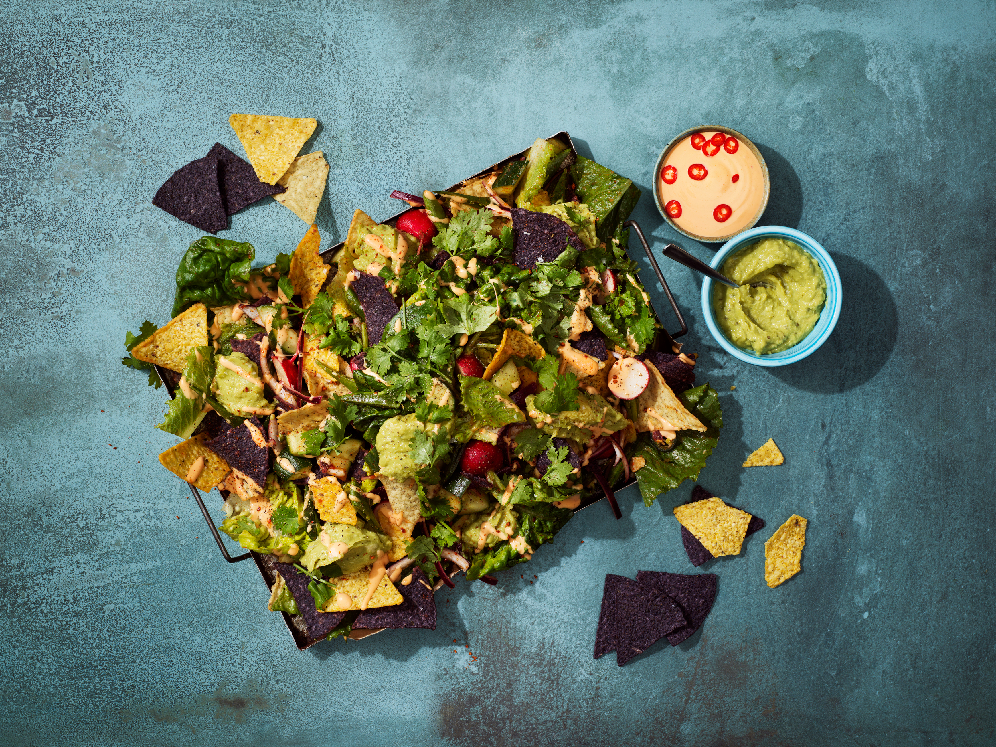 Produktfoto: El Taco Truck en bricka med nachos och topping på ett mörgrått bord