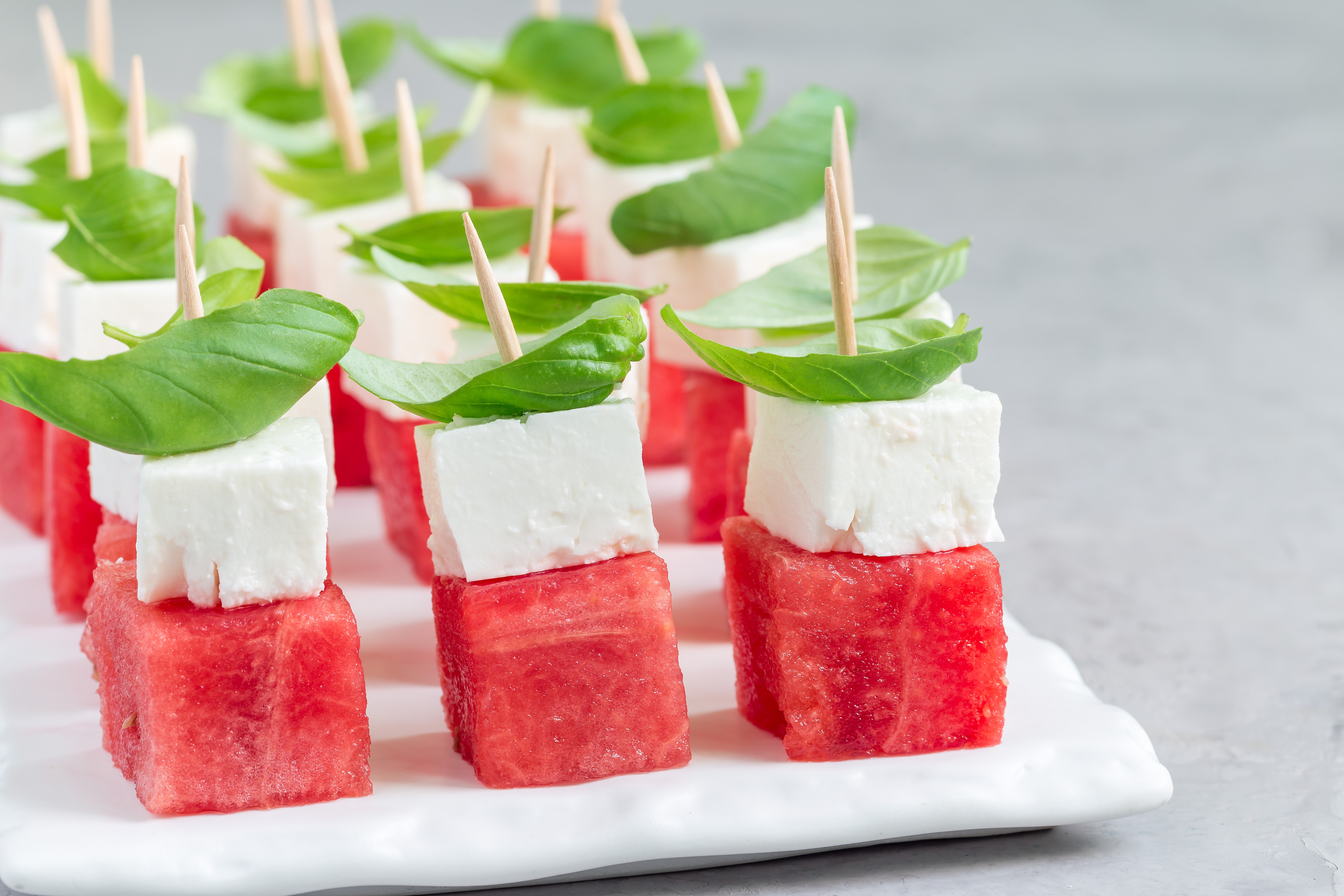 Foto: iuliia_n/Shutterstock Snittar med melon, vegansk fetaost och basilika på ett vitt fat.