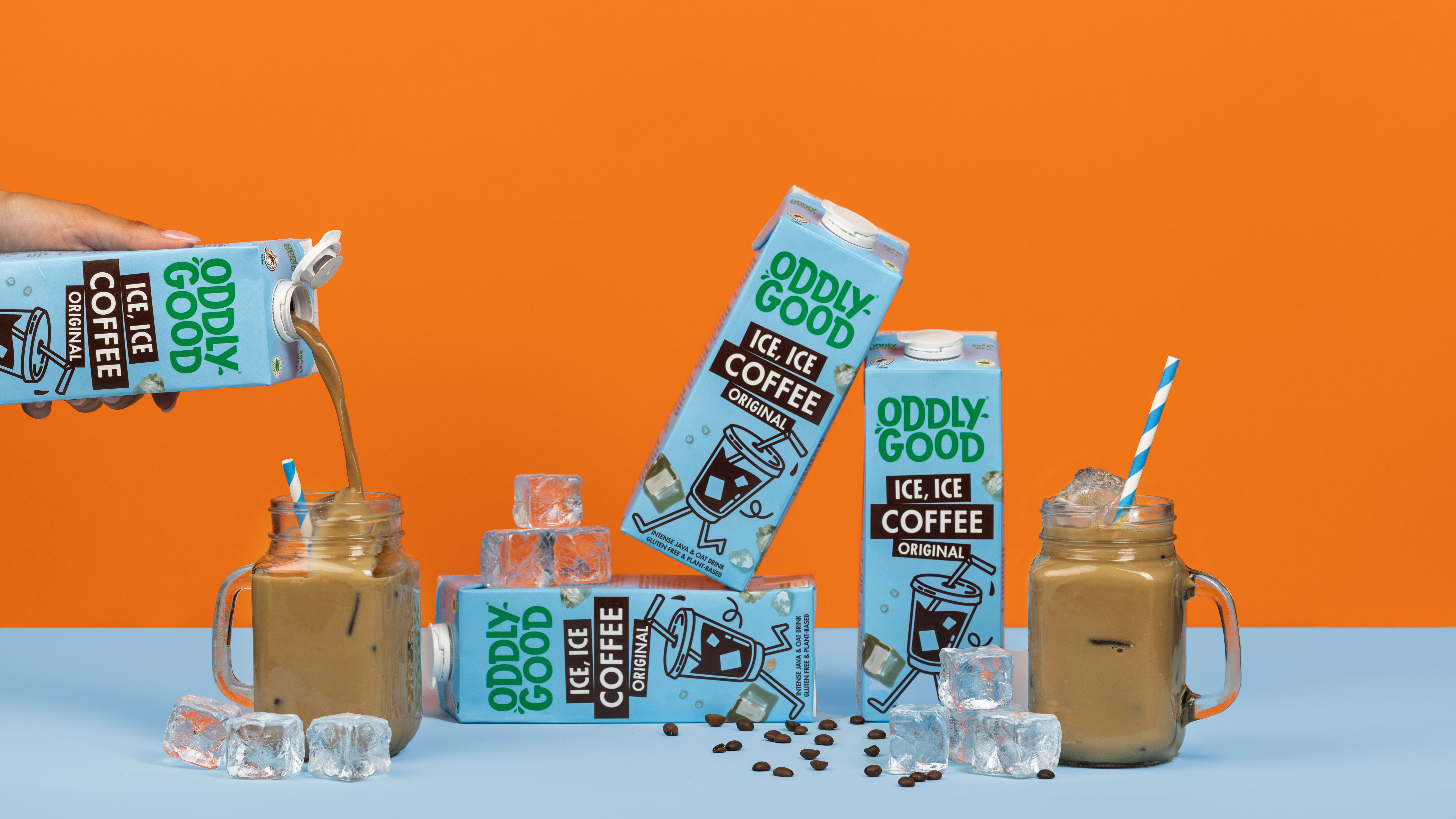 Produktfoto: Oddlygood Förpackningar med växtdryck och glas med iskaffe mot en orange bakgrund.