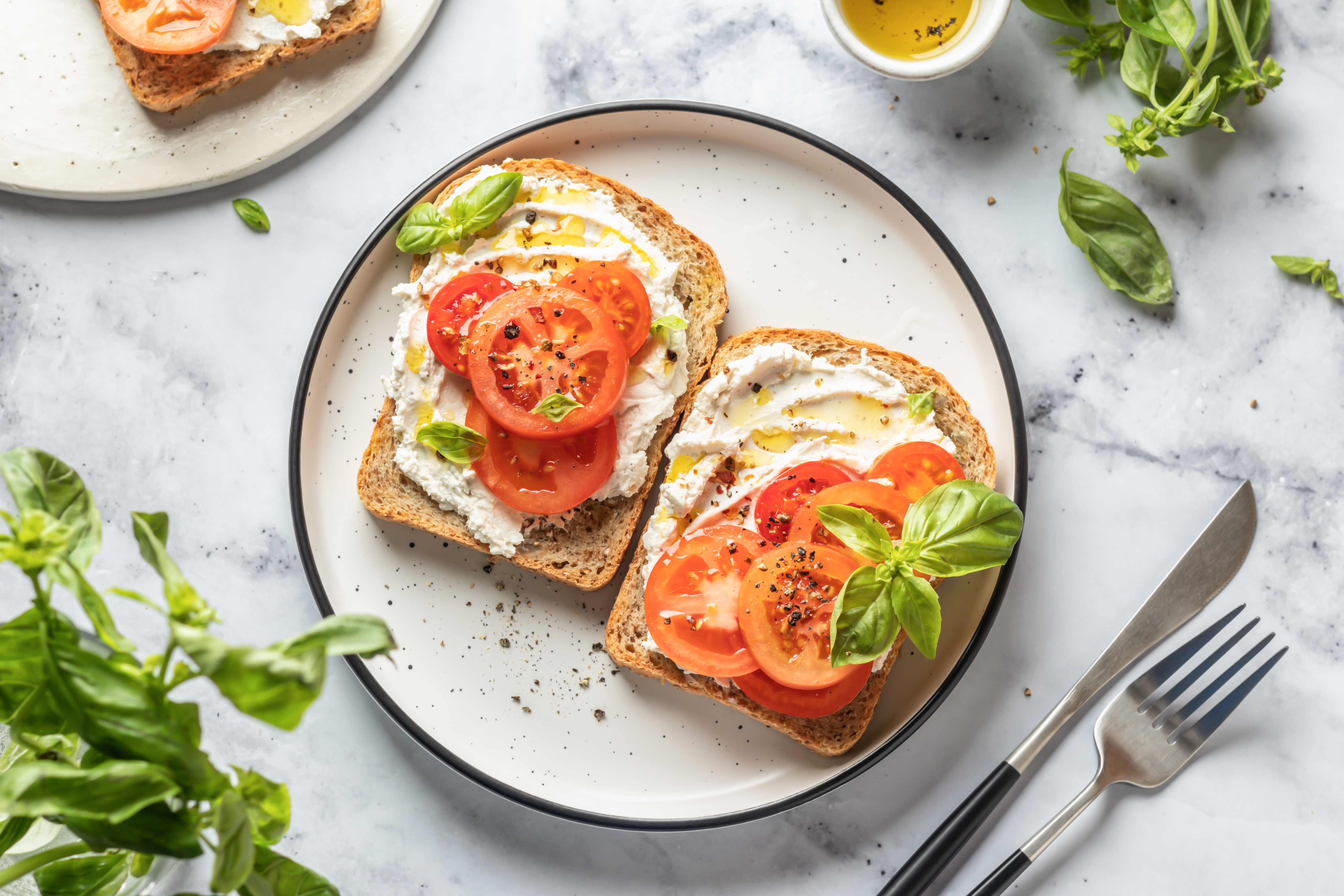 Foto: HANNA HAFARAVA/Shutterstock En tallrik med två smörgåsar med vegansk cream cheese och tomater, toppade med basilika