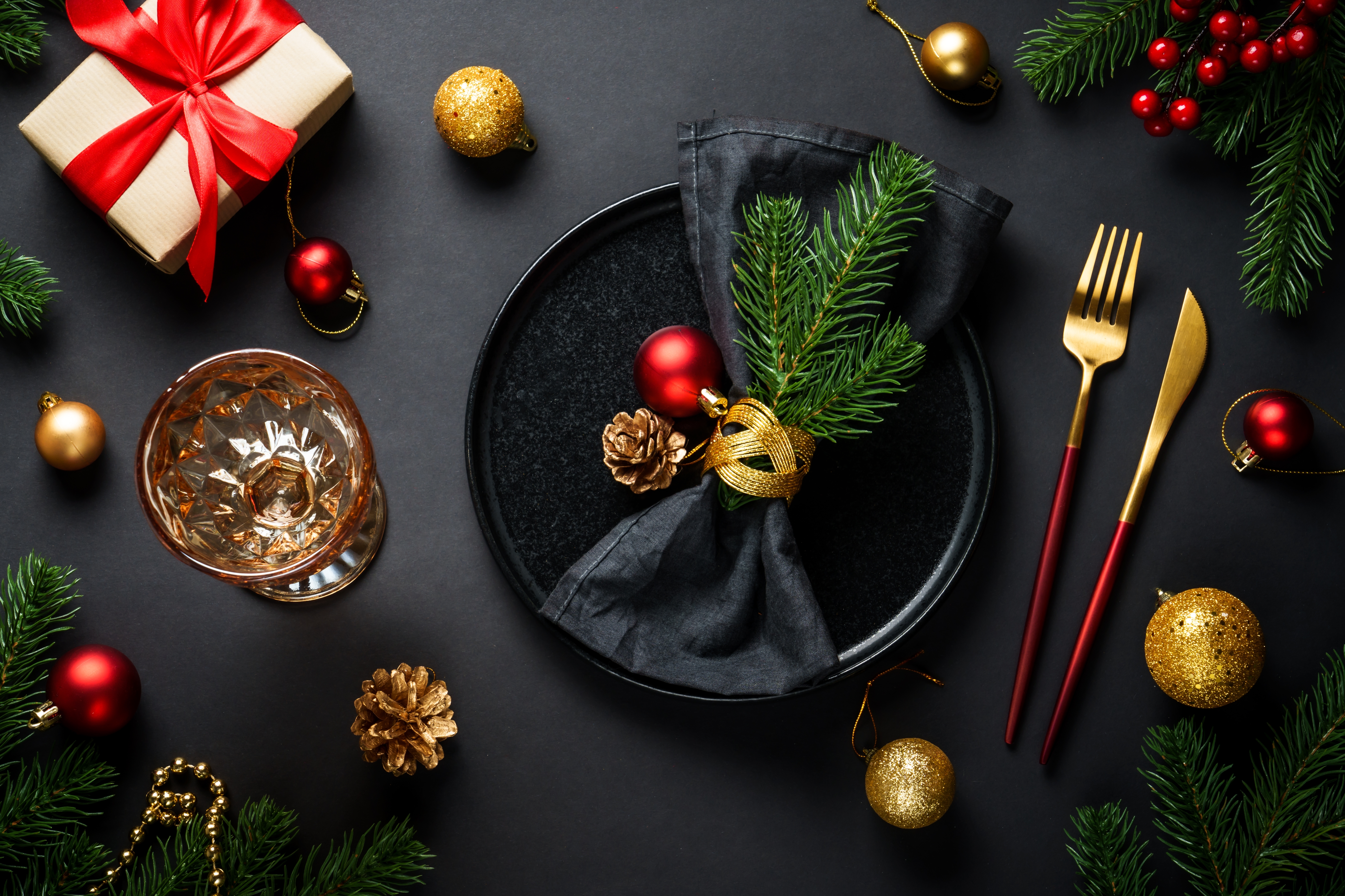 Foto: nadianb/Shutterstock Christmas table setting with black plate, wine glass, cutlery and holidays decorations.