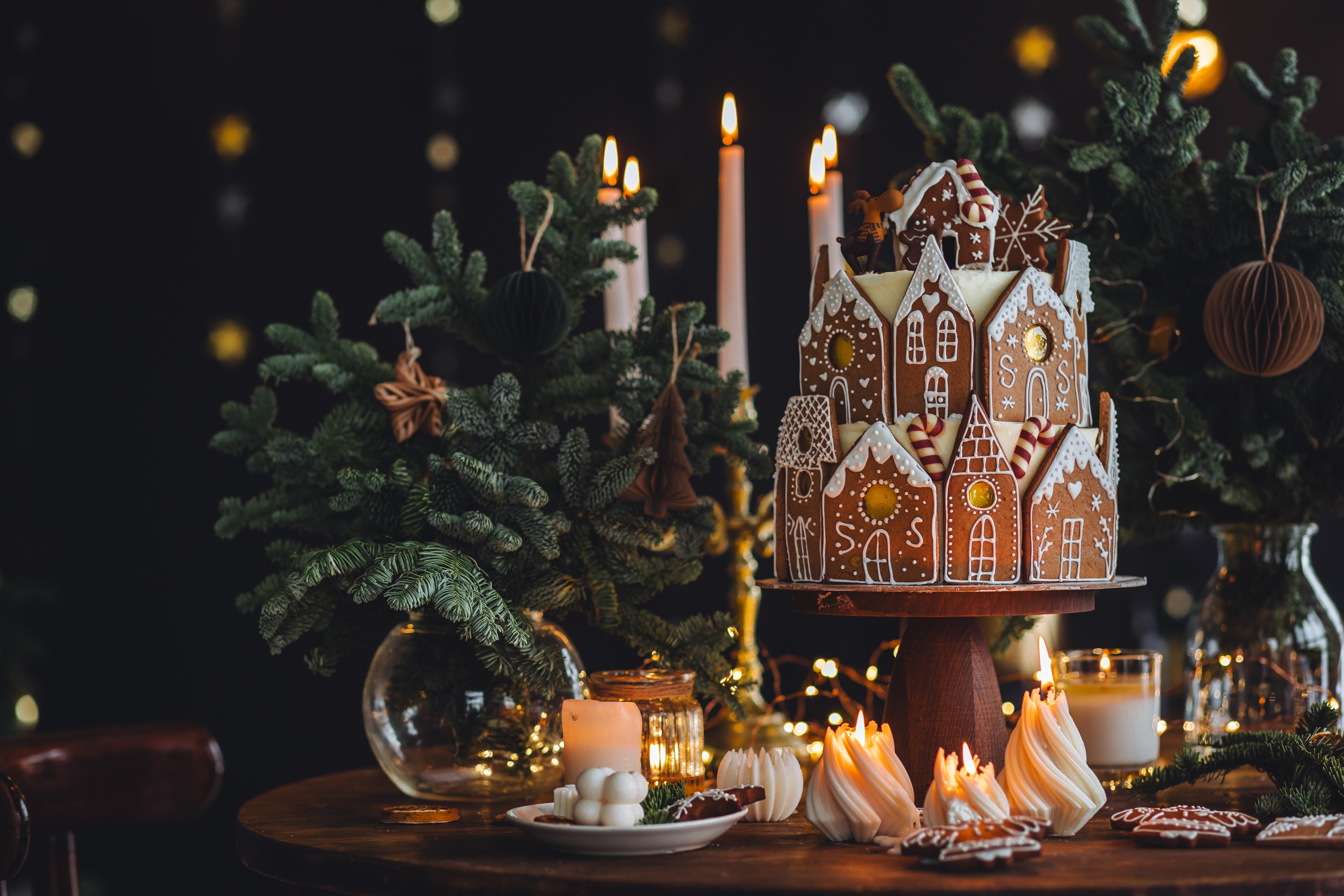 Foto: Vera Prokhorova/Shutterstock Christmas and New Year beautiful elegant family dinner table setting decorated with candles, fir tree branches, handmade craft toys. Gorgeous big homemade cake with gingerbread houses as centrepiece