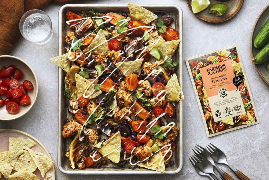 Produktfoto: Eat More Greens En plåt med dressade nachos på ett ljust bord med tillbehör på sidorna