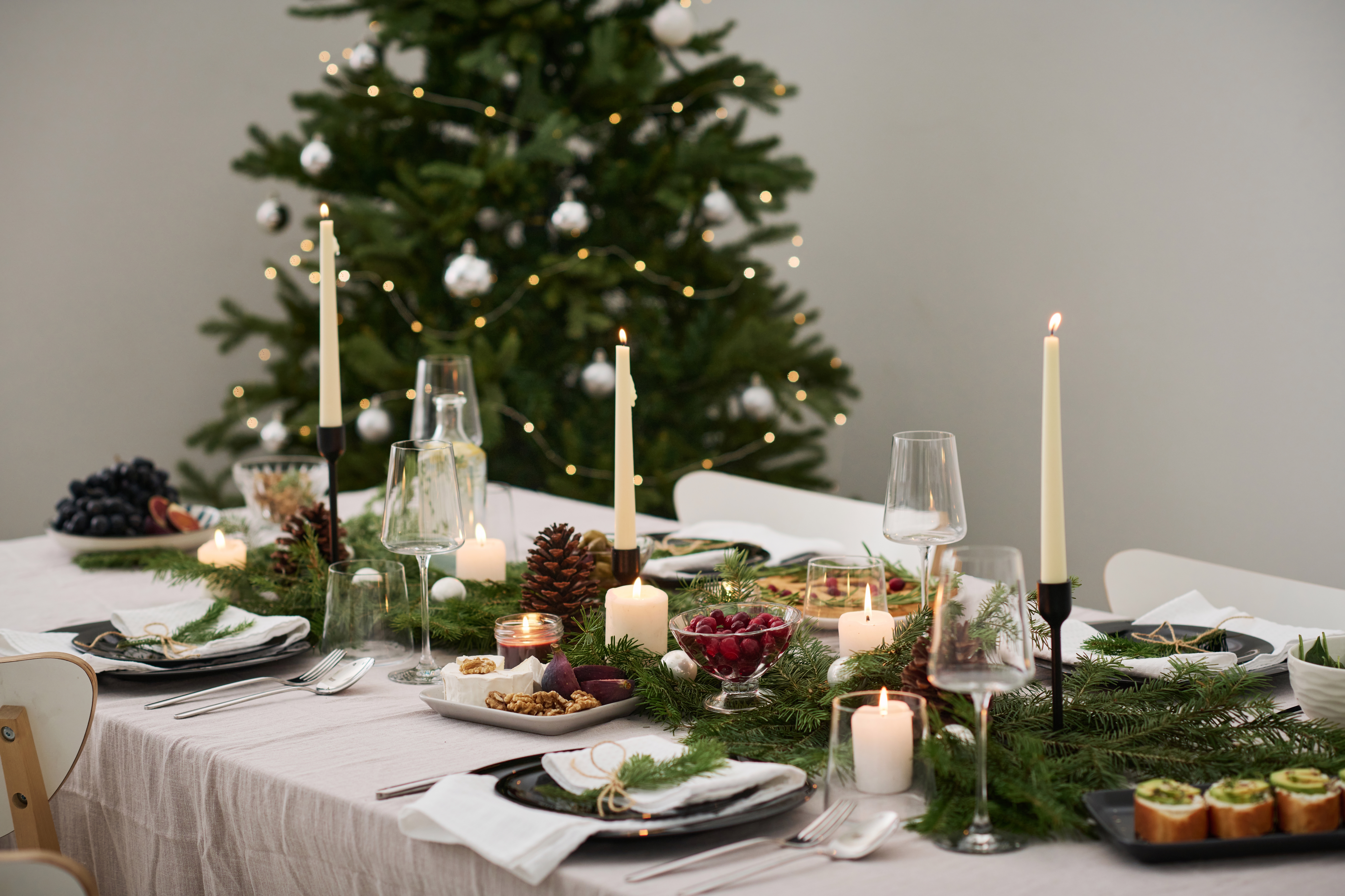 Ett uppdukat bord med julpynt och julgran i bakgrunden