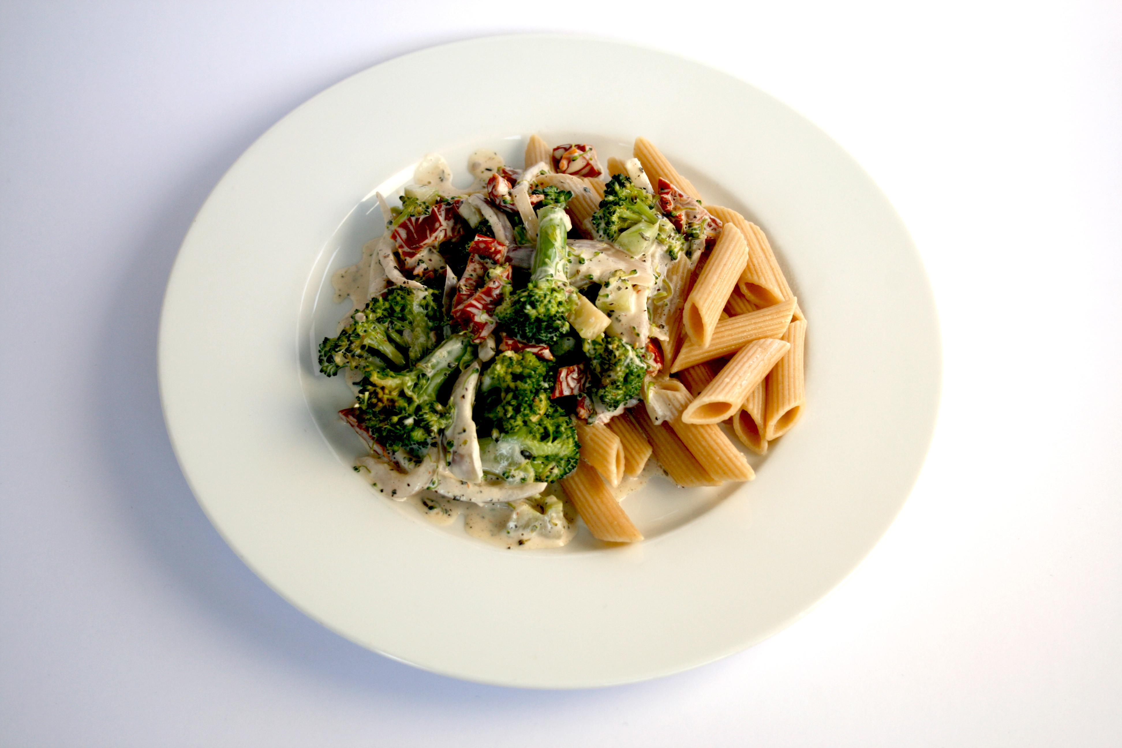Pasta med broccoli och soltorkade tomater Pasta med broccoli och soltorkade tomater på en vit tallrik