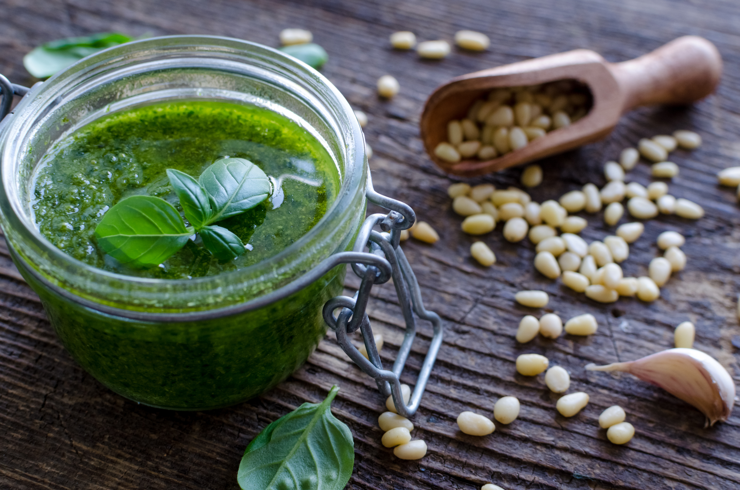 Foto: Shutterstock Nelli Syrotynska Bild på grönpesto på ett bord med utrströdda pinjenötter.