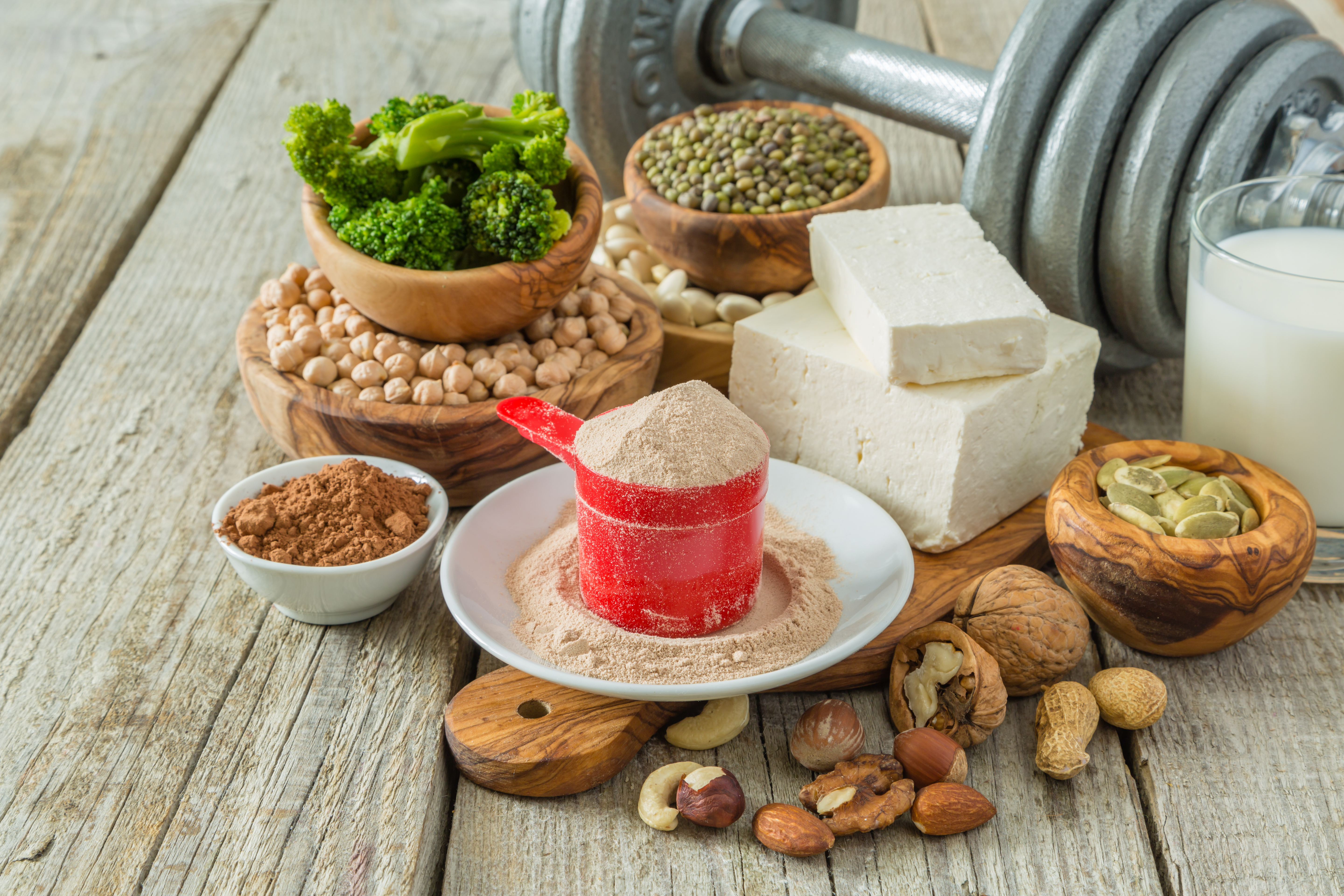 Foto: Shutterstock Oleksandra Naumenko Bild på olika vegetabilsika proteinkällor och en träningsvikt i bakgrunden