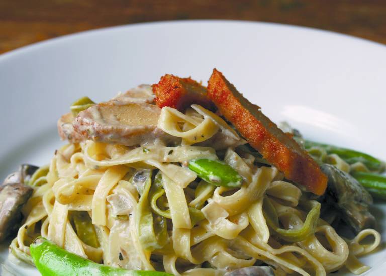 Pasta med sojakyckling och sockerärtor på en vit tallrik