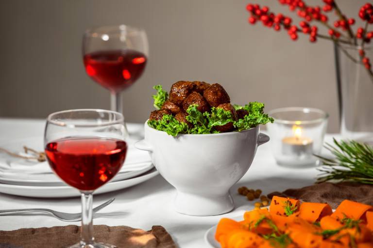 Veganska köttbullar i en vit skål på ett dukat bord