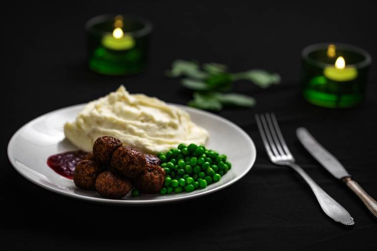 veganska köttbullar, potatismos och gröna ärtor på en vit tallrik 