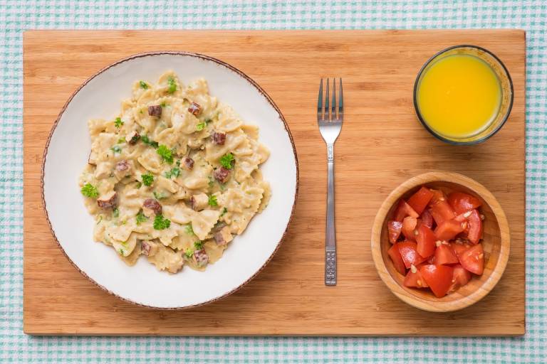 Vegansk carbonara med tofu på ett bord tillsammans med juice och tomatsallad