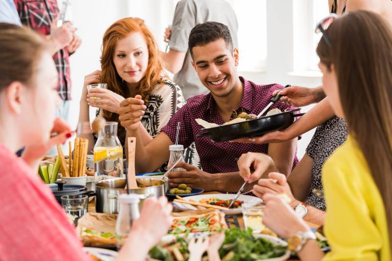 Ett gäng vänner samlade kring ett bord och äter veganskt mat