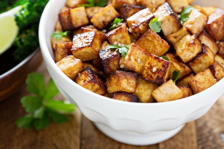 Rör stekt tofu i en skål med sesam och gröna