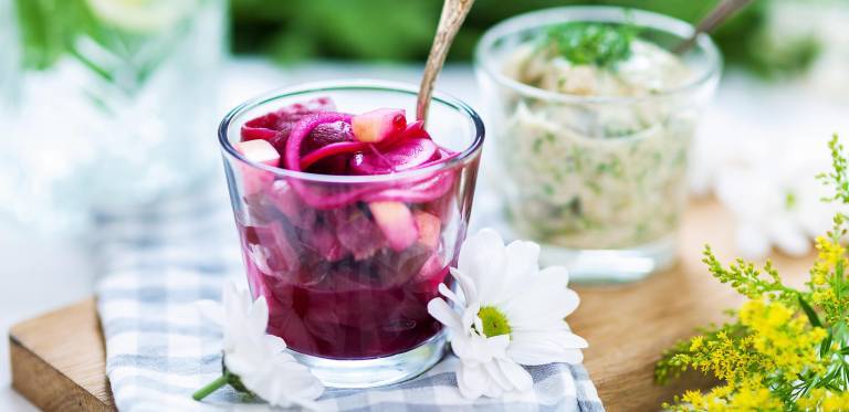 Vegansk sill med rödbetslag, i glas på somrigt dekorerat bord.