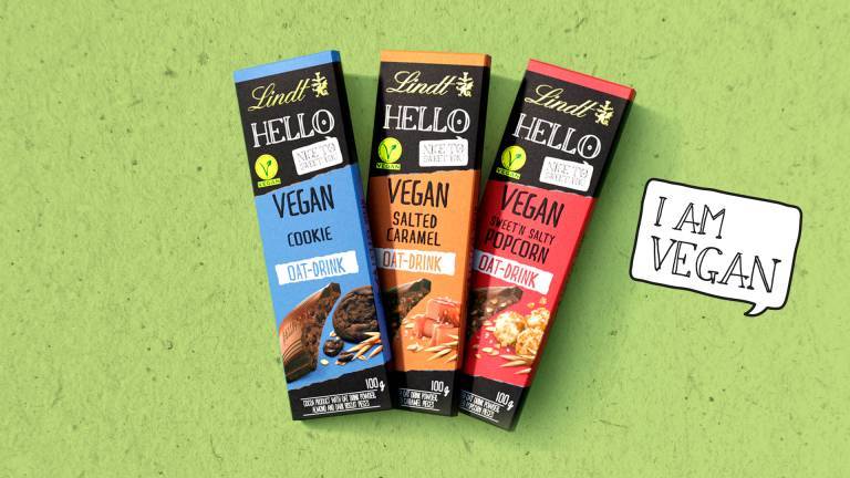 Den veganska chokladen Lindt Hello Vegan i tre olika smaker, i förpacknging mot grön bakgrund.