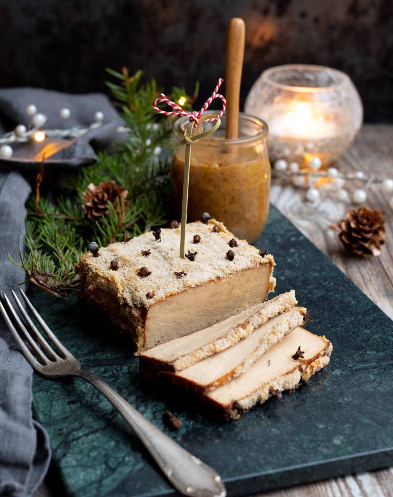Griljerad tofu på en mörk marmorplatta på ett uppdukat julbord. 