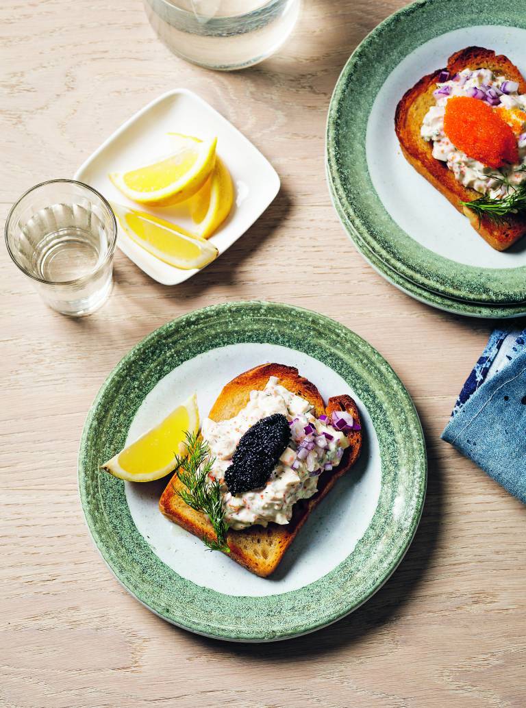 Skagenröra på toast på två tallrikar på ett ljust träbord