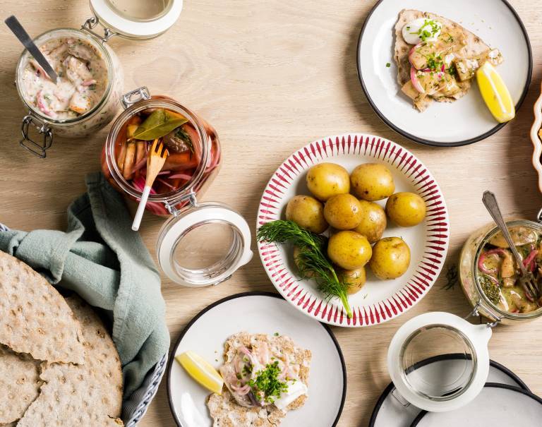 Flera olika veganska sillar uppdukade på ett bord med kokt potatis och knäckebröd. 