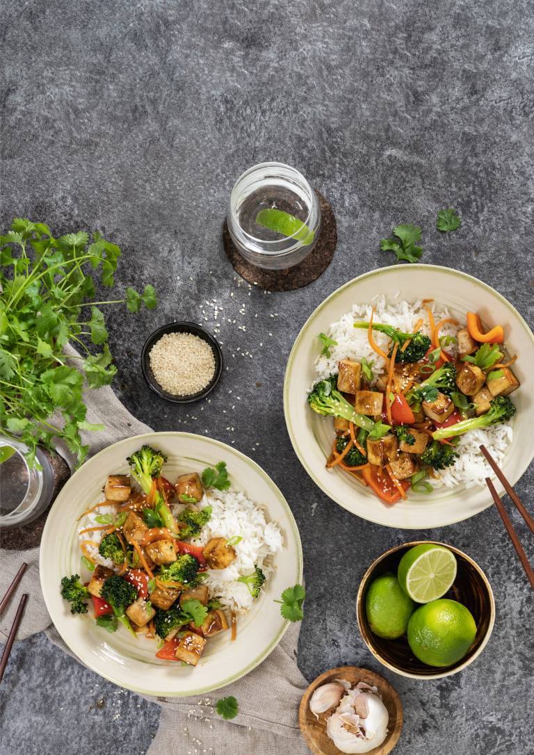 Wok med ros i två tallrikar taget ovanifrån mot ett grått bord