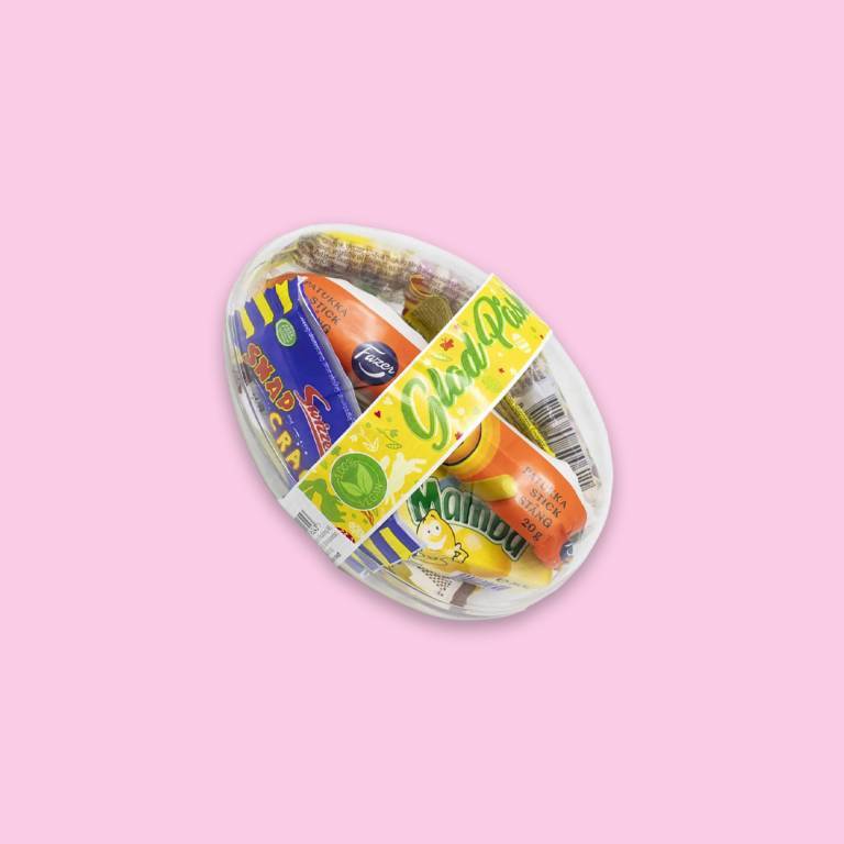 ett påskägg i plast med vegansk godis i mot en ljusrosa bakgrund