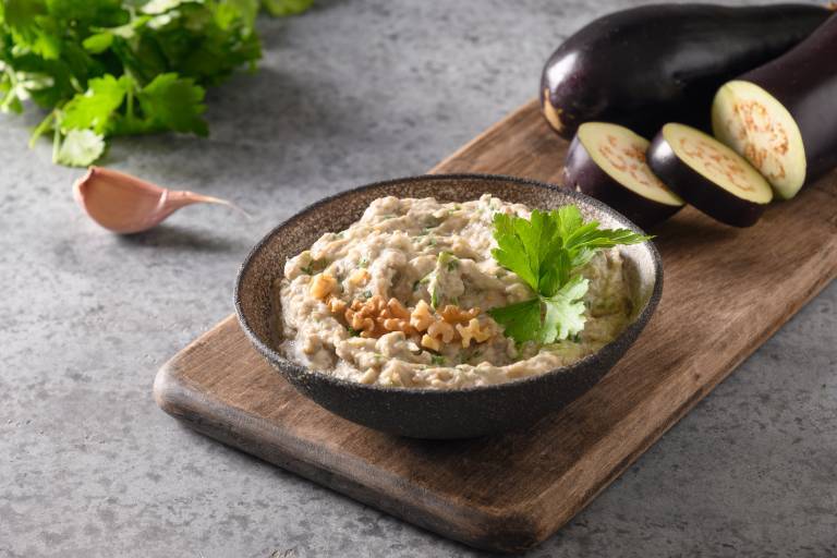 Baba ganoush i en tallrik på en skärbräda. 
