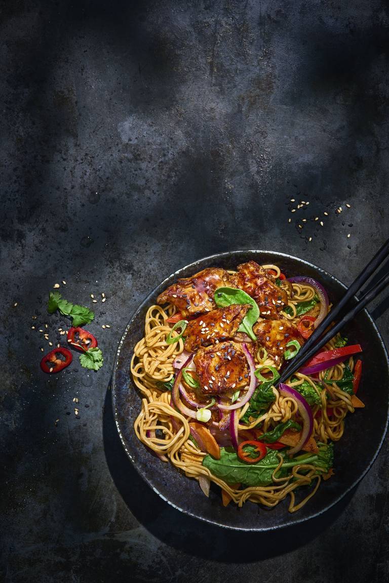 Koreansk nudelwok i en svart tallrik på ett svart bord