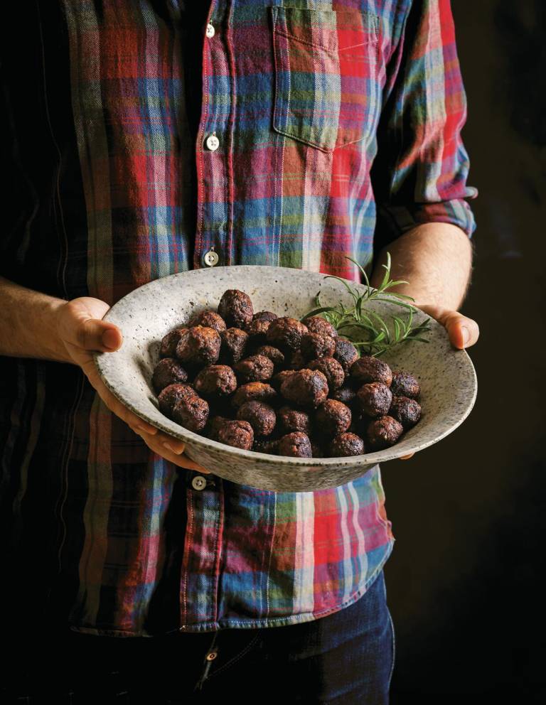 En man som håller i en skål med veganska julköttbullar