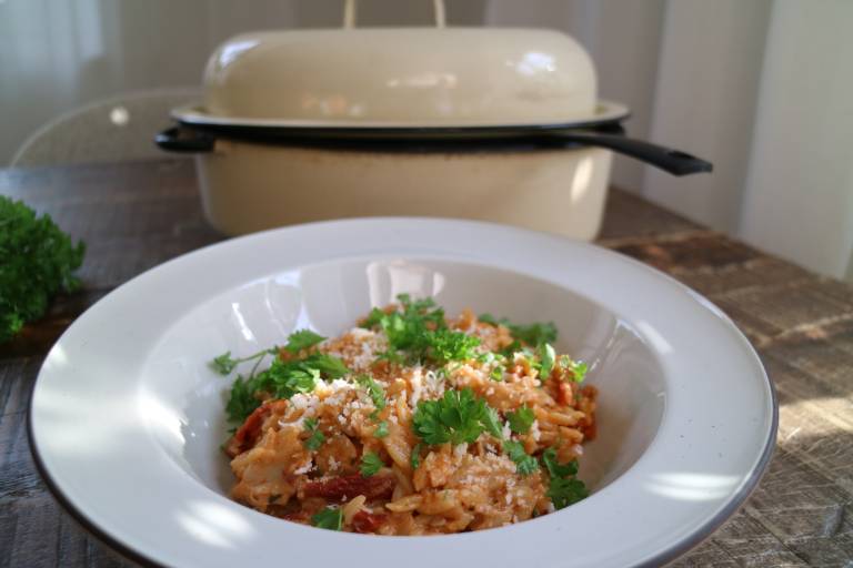 En tallrik risoni framför en gryta